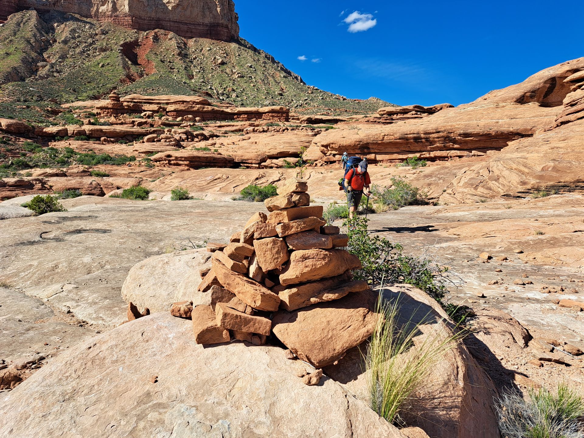 A person is standing next to a pile of rocks in the desert.