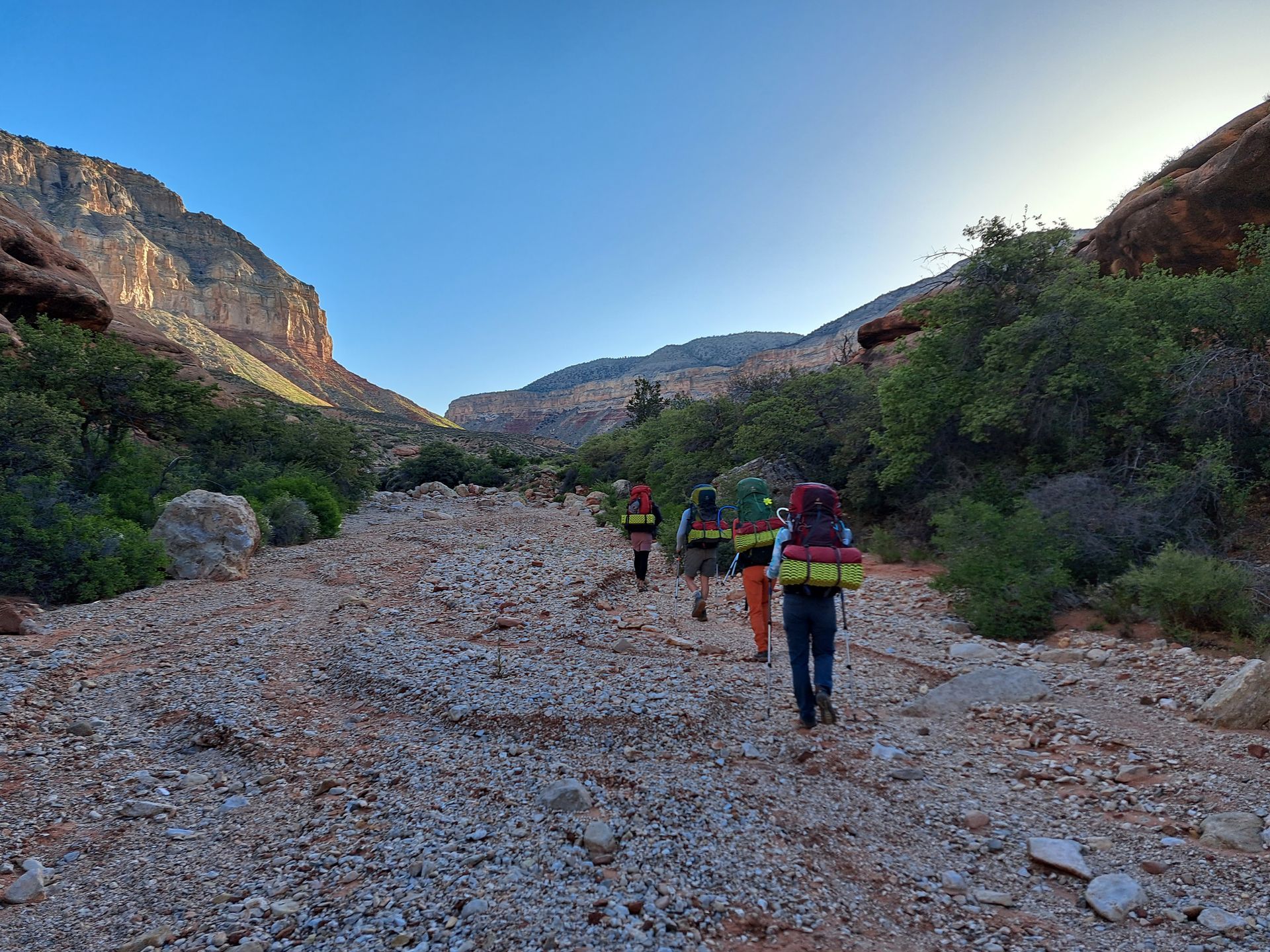 A group of people are walking down a rocky trail in the mountains.