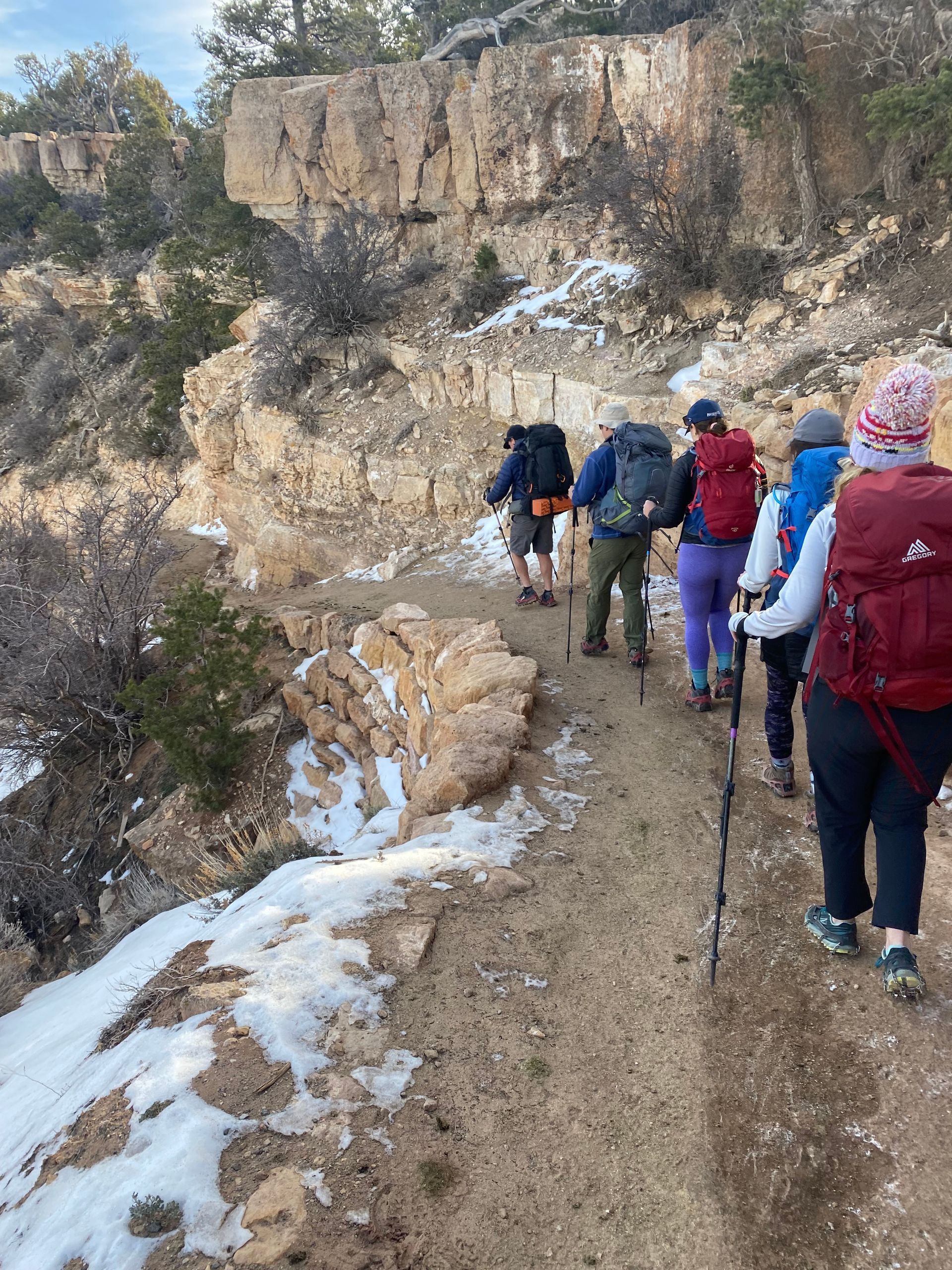 A group of people are hiking down a dirt path.