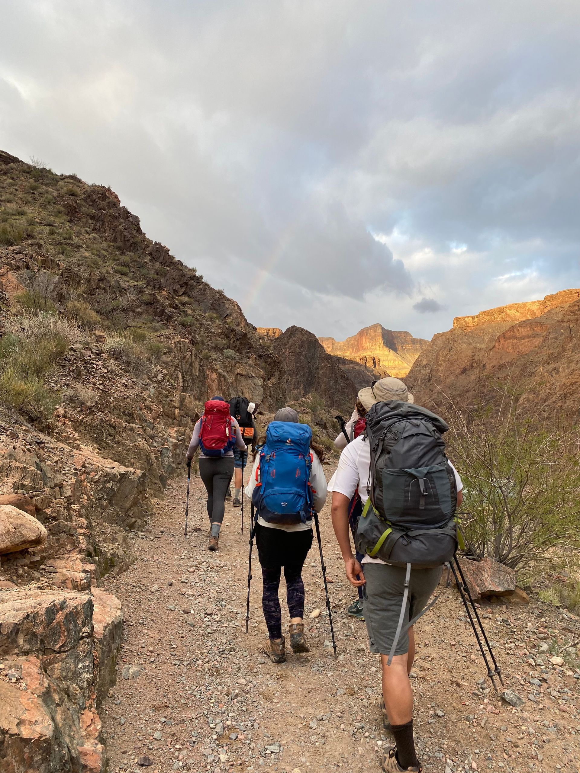 A group of people with backpacks are hiking down a dirt path.