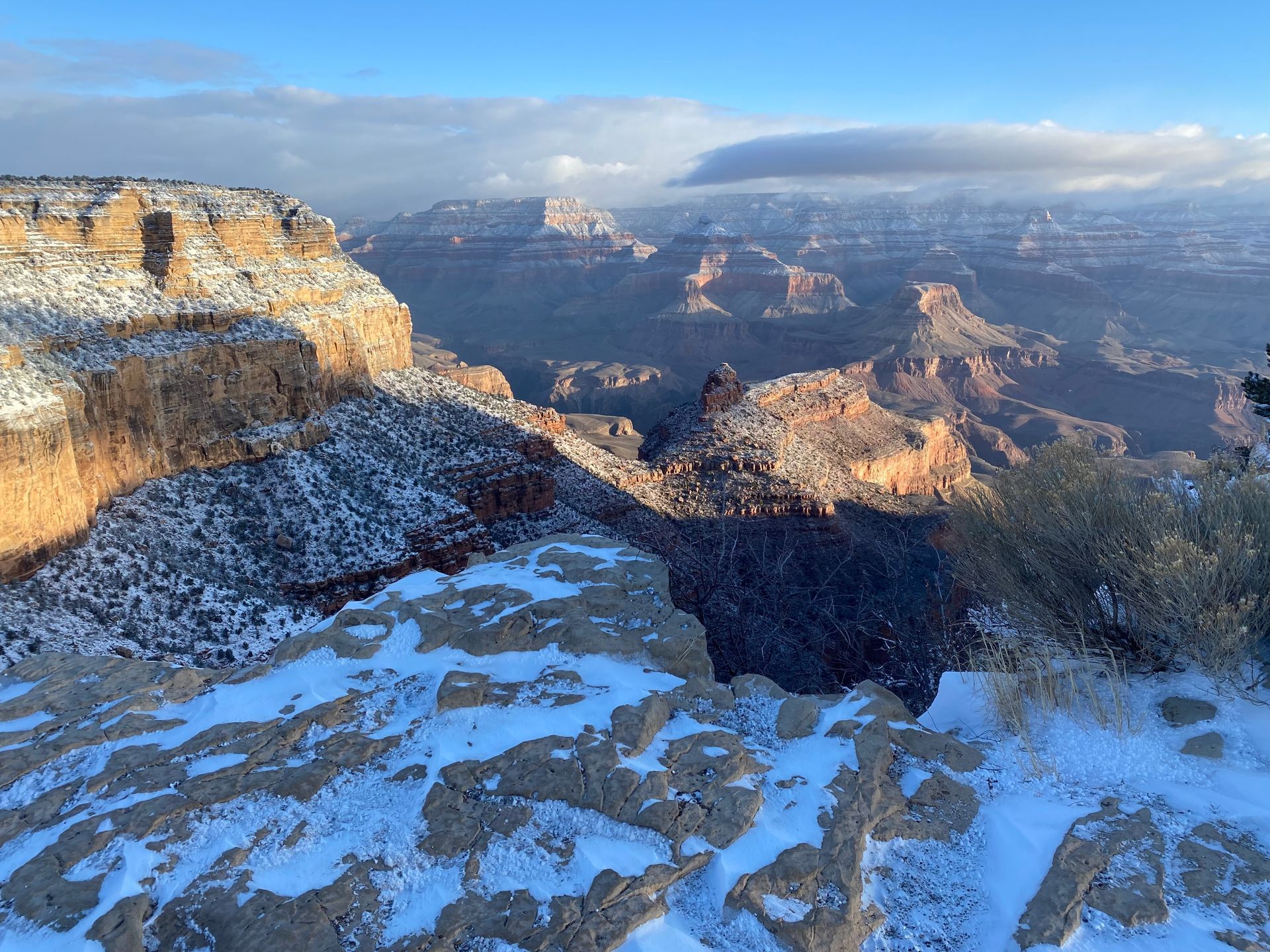 The grand canyon is covered in snow on a sunny day.