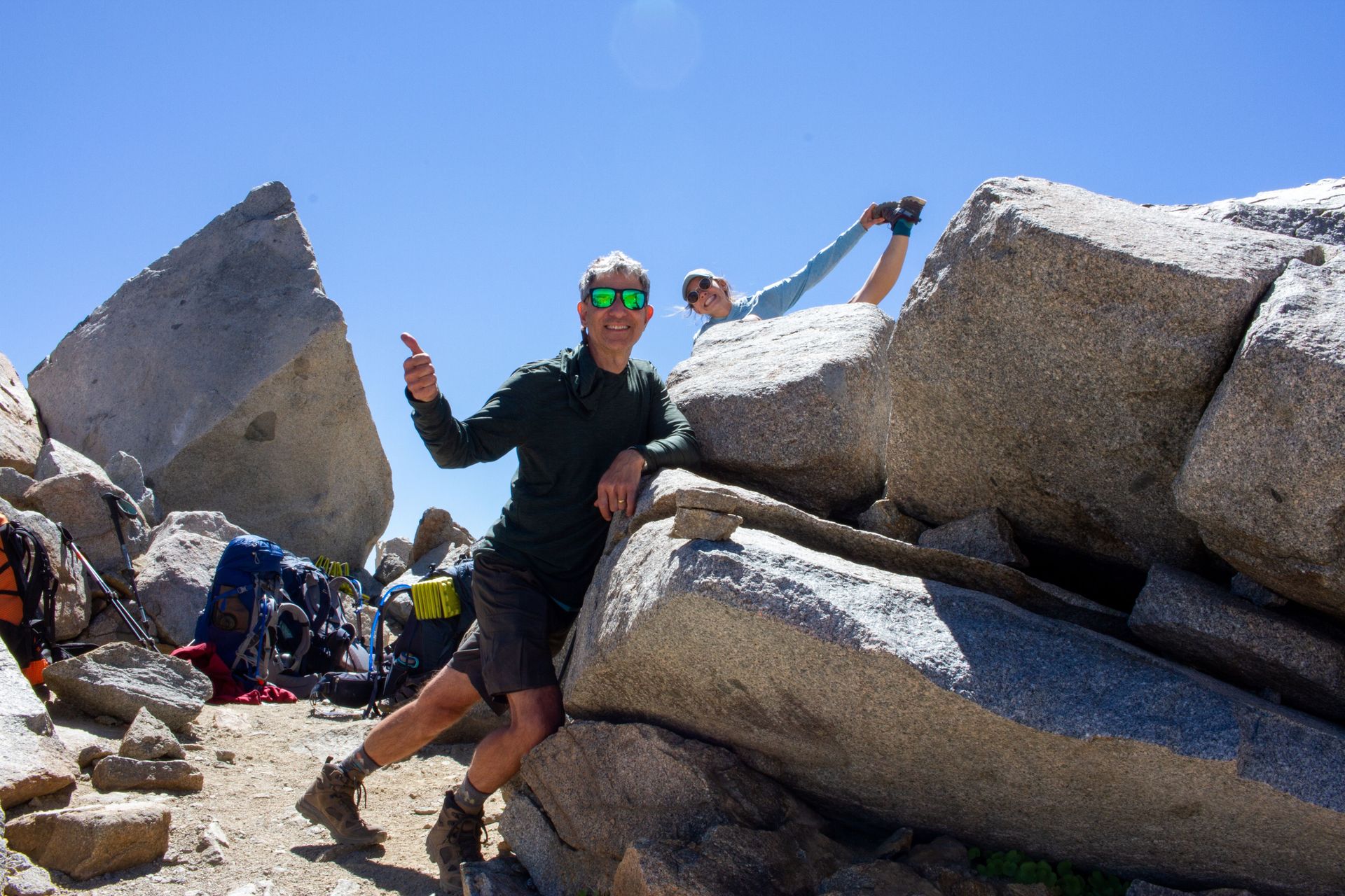 A man is standing on top of a large rock.