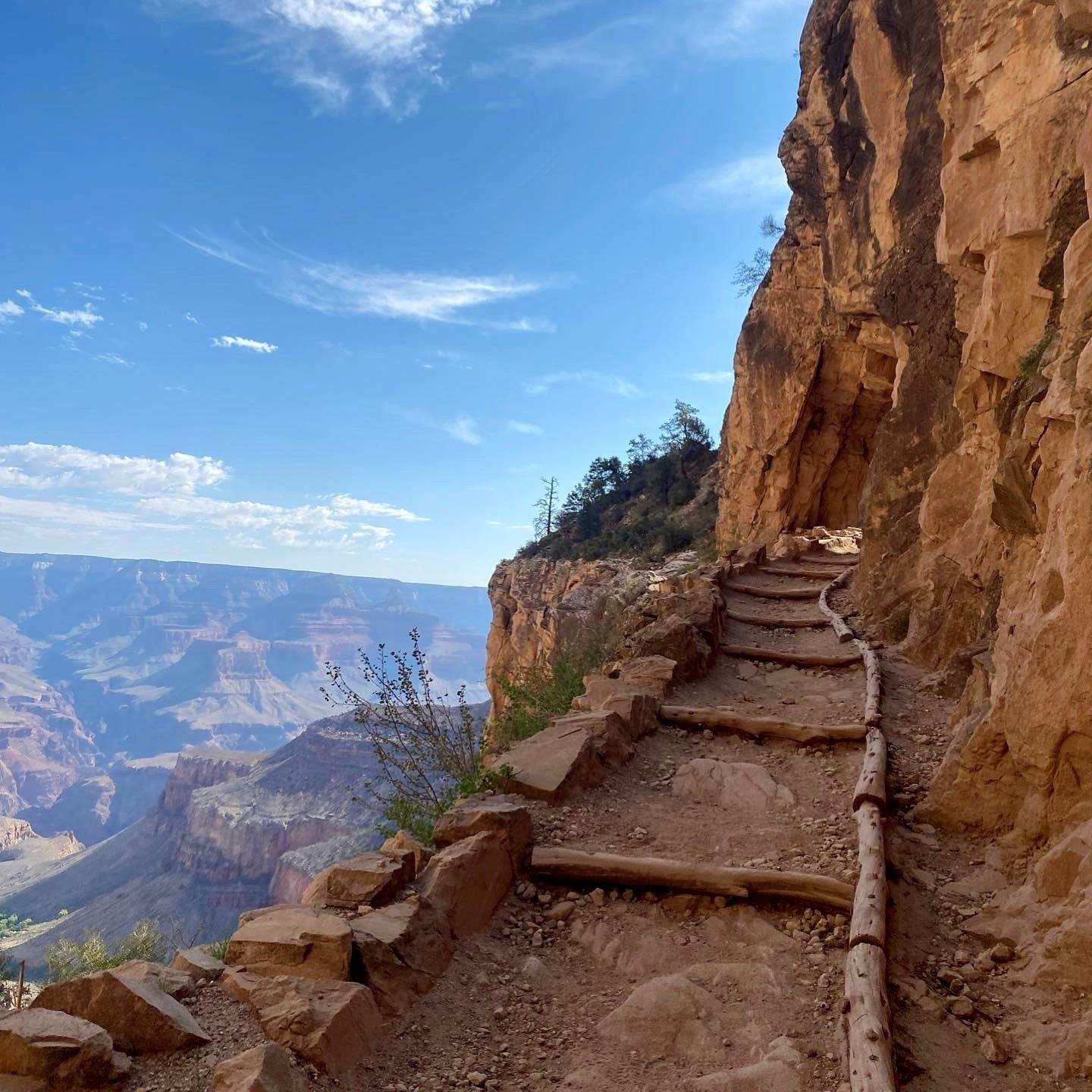 A trail going up a cliff with a view of the grand canyon