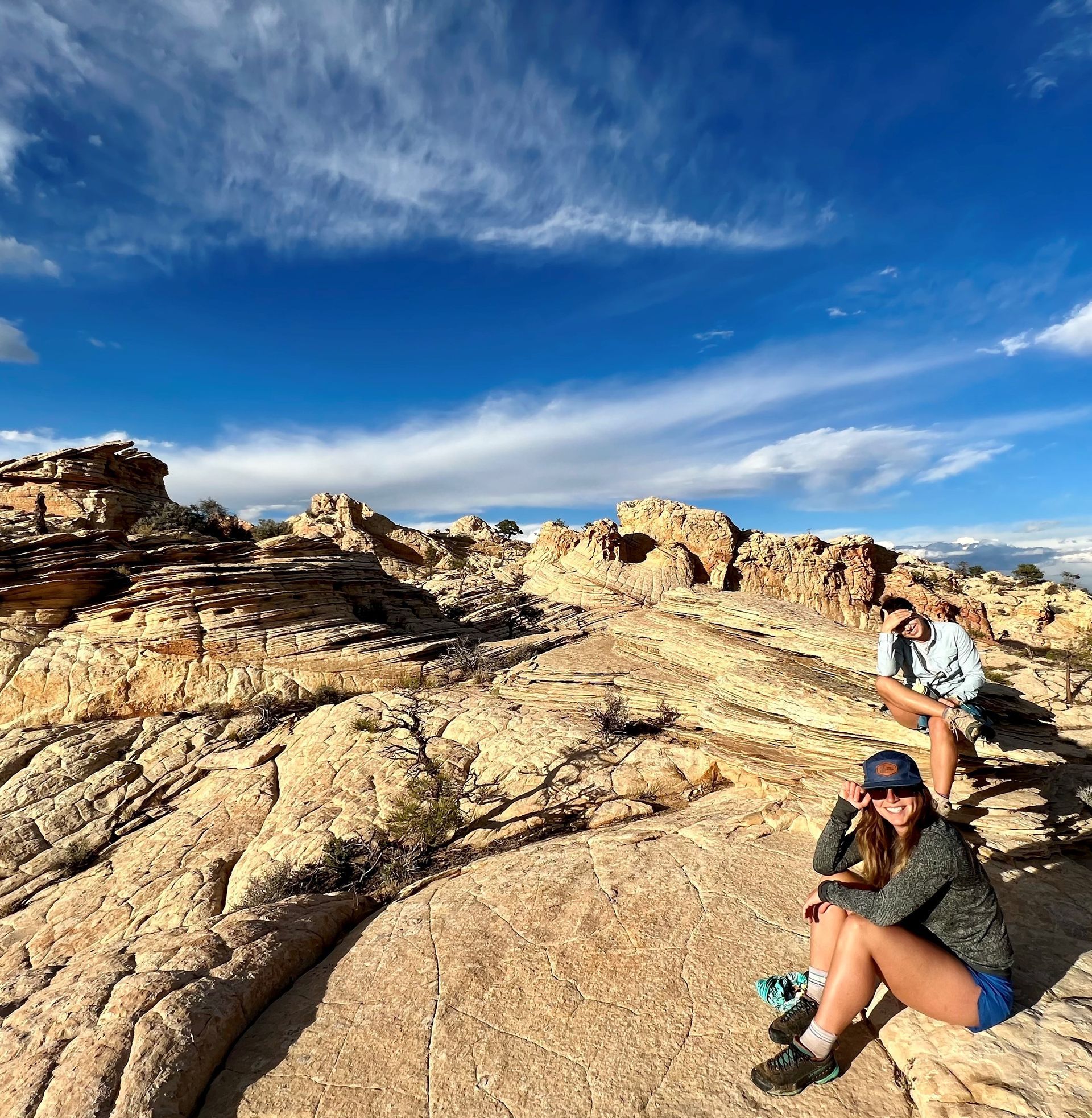 Two people are sitting on a rock in the desert