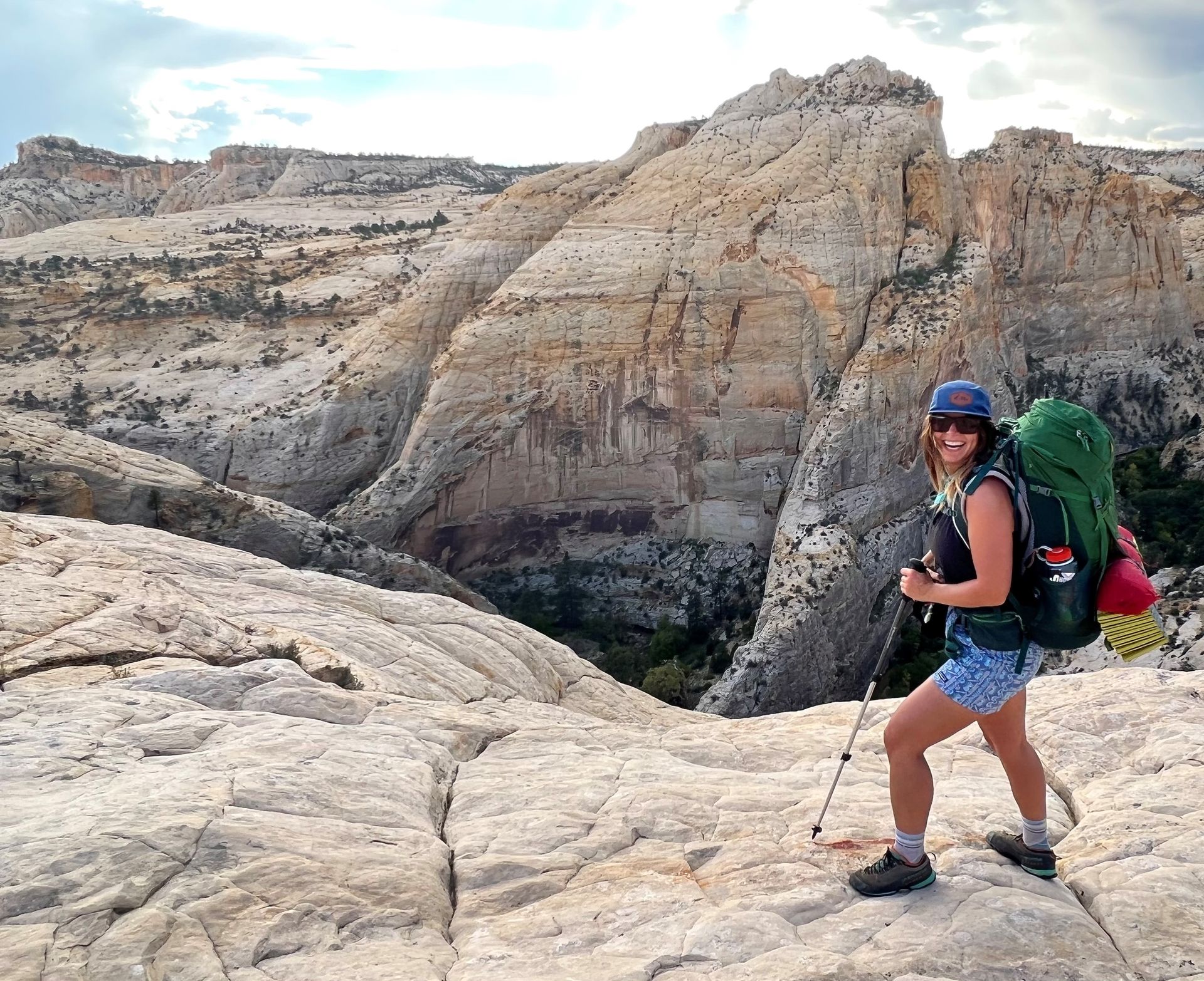 A woman with a backpack is standing on a rocky hillside