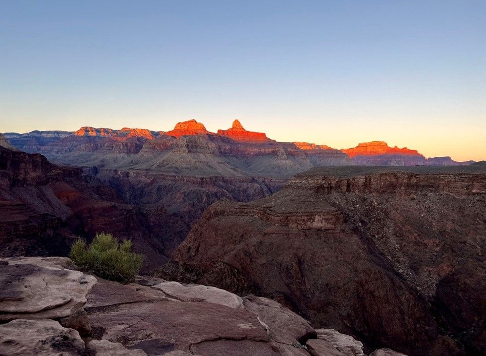 A view of the grand canyon at sunset with mountains in the background.