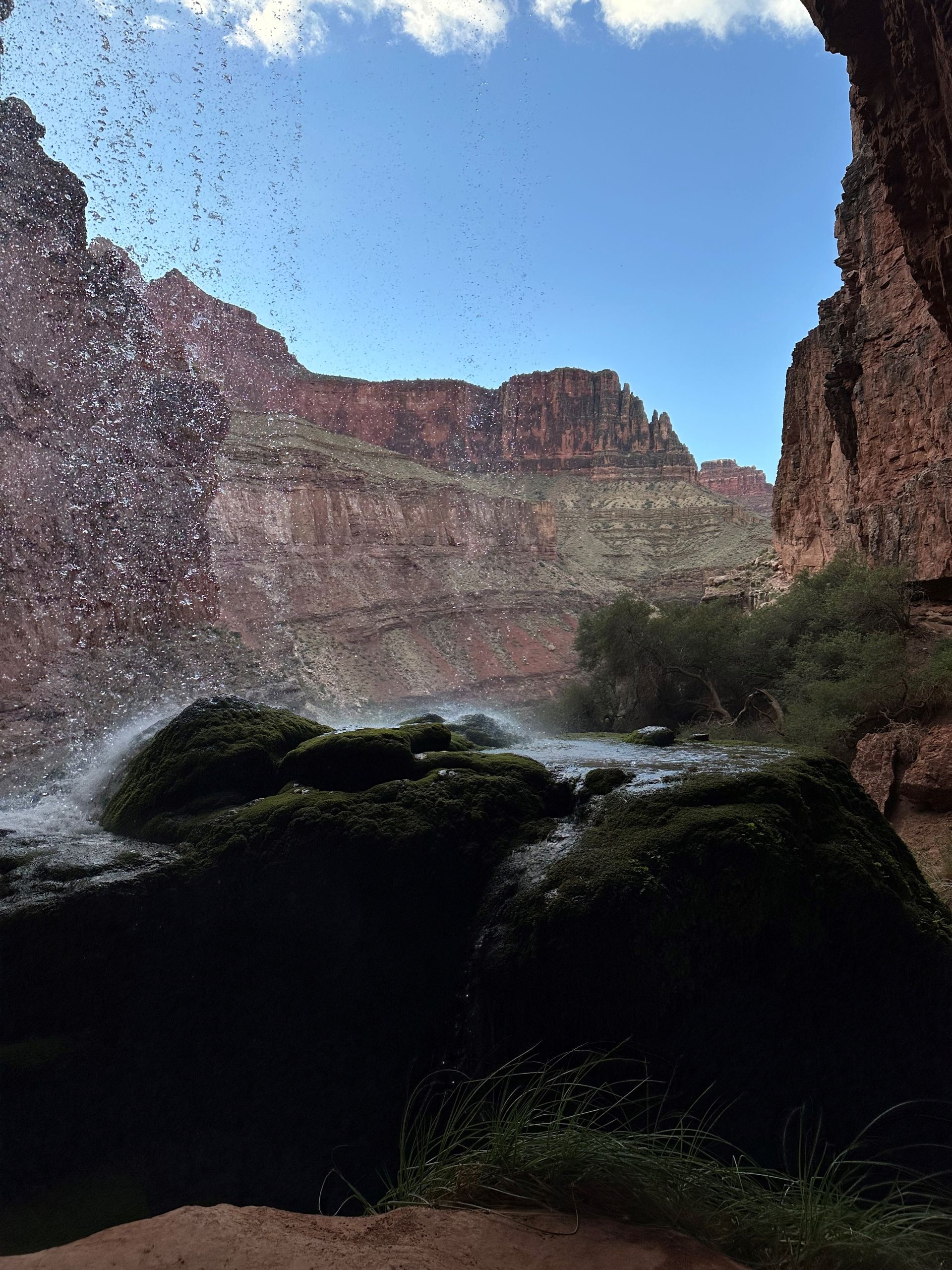 A waterfall in the middle of a canyon with a blue sky in the background.