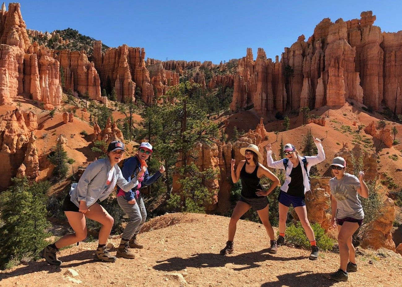 A group of people are jumping in the air in front of a mountain.