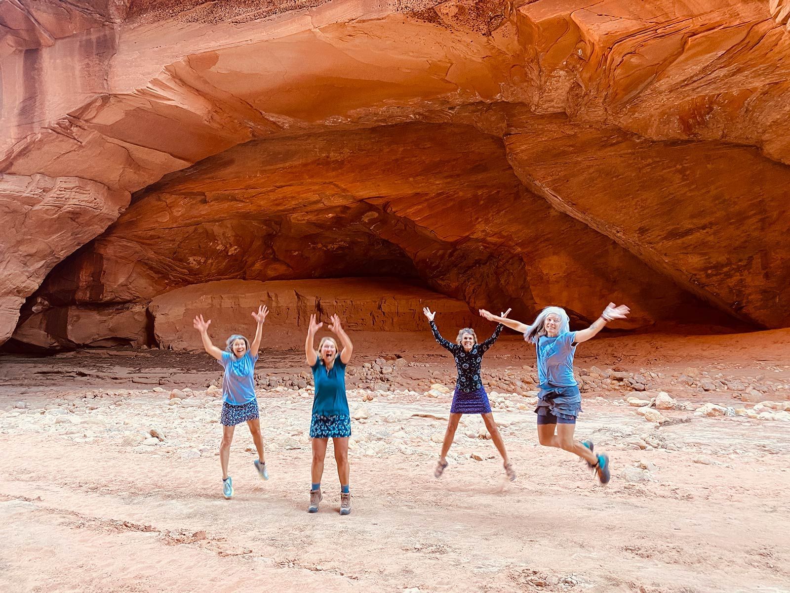 Ladies jumping in the air in front of a cave.