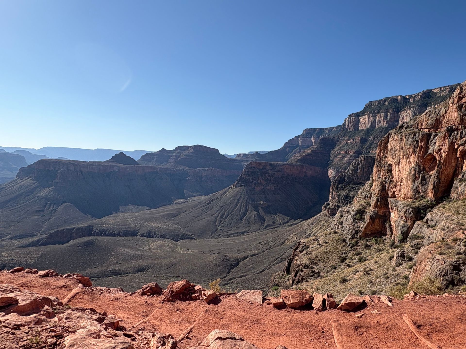 Vast canyon landscape with red rock formations under a clear blue sky.