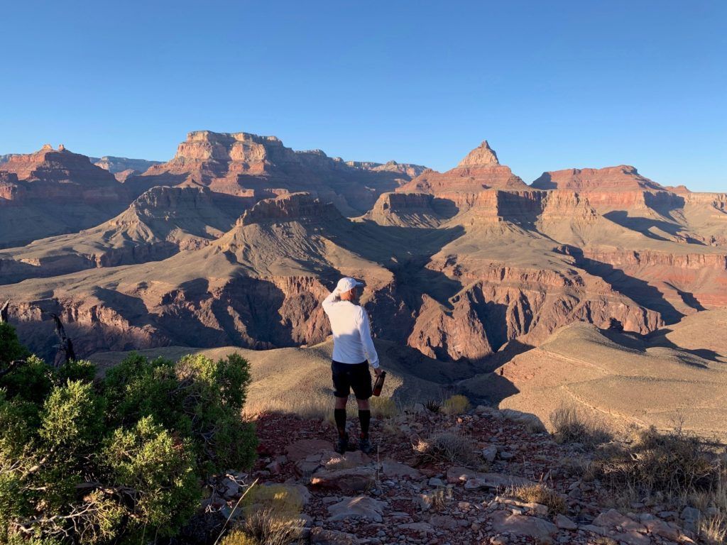 A man is standing on top of a mountain looking at the mountains.