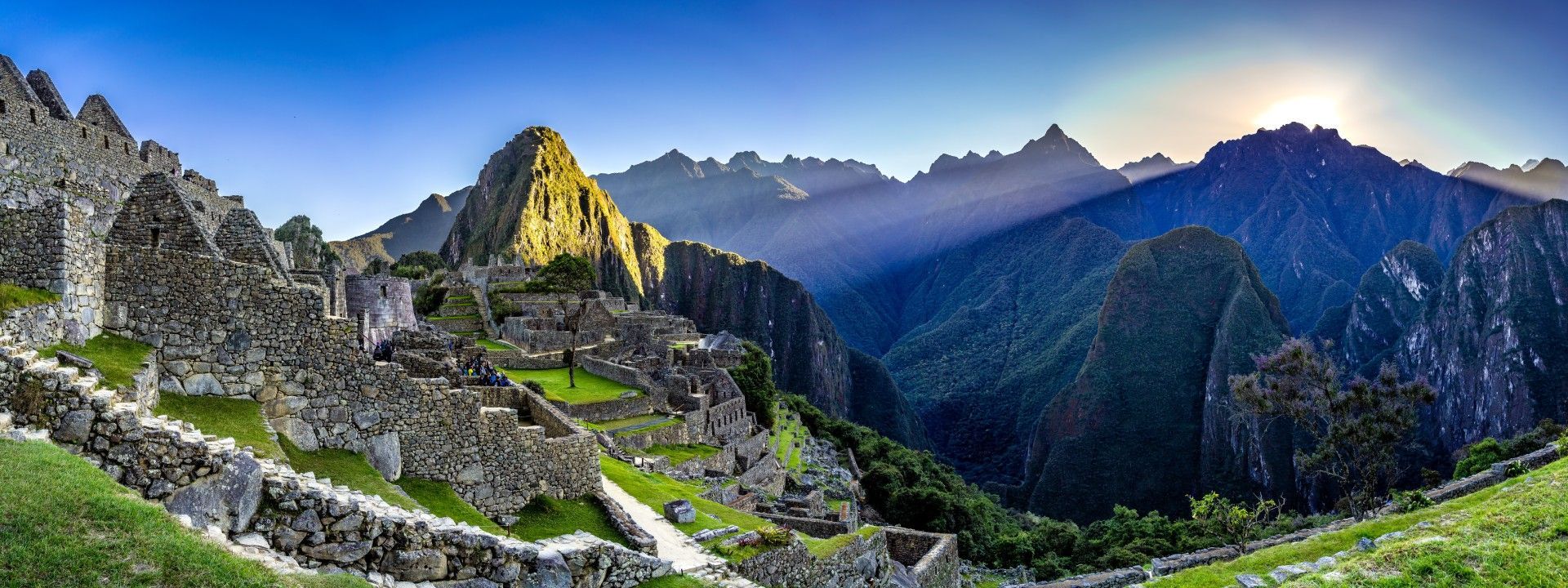 Machu Picchu, ancient Incan city in the Andes mountains, Peru. Ruins and lush green vegetation under blue sky.