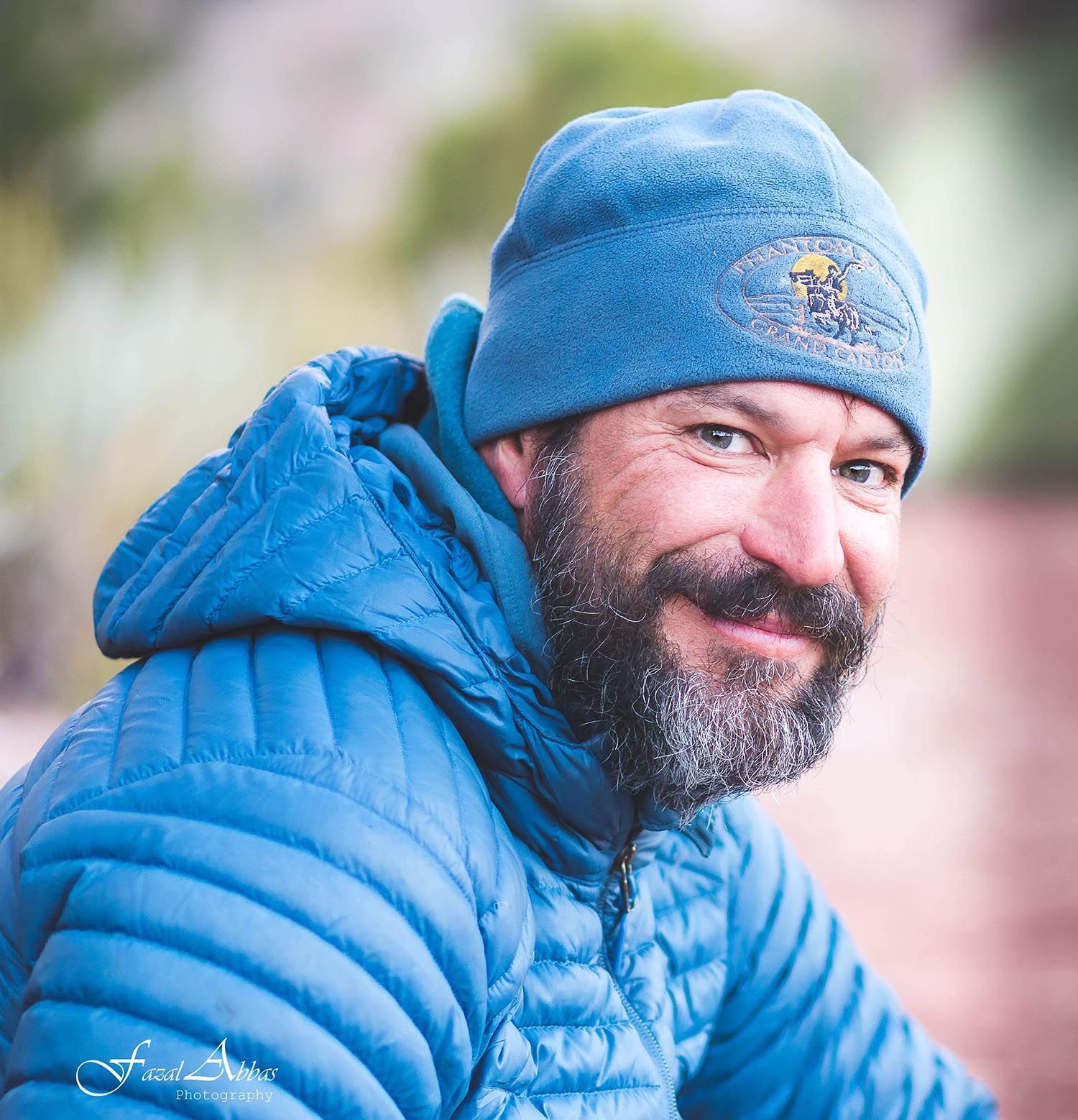 A man with a beard is wearing a blue jacket and a blue beanie.