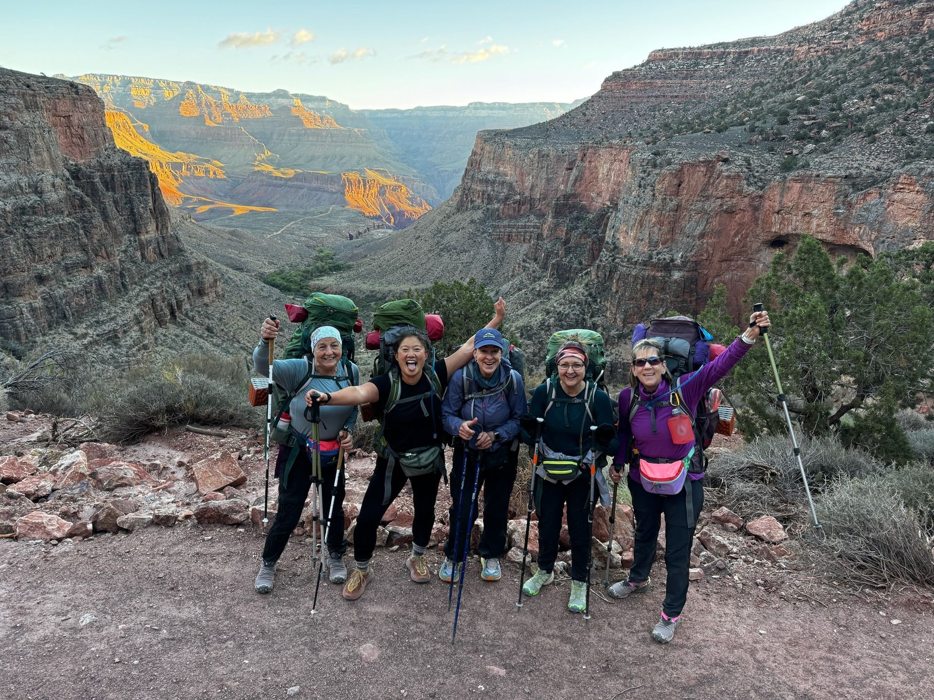 A group of women are standing next to each other on top of a mountain.