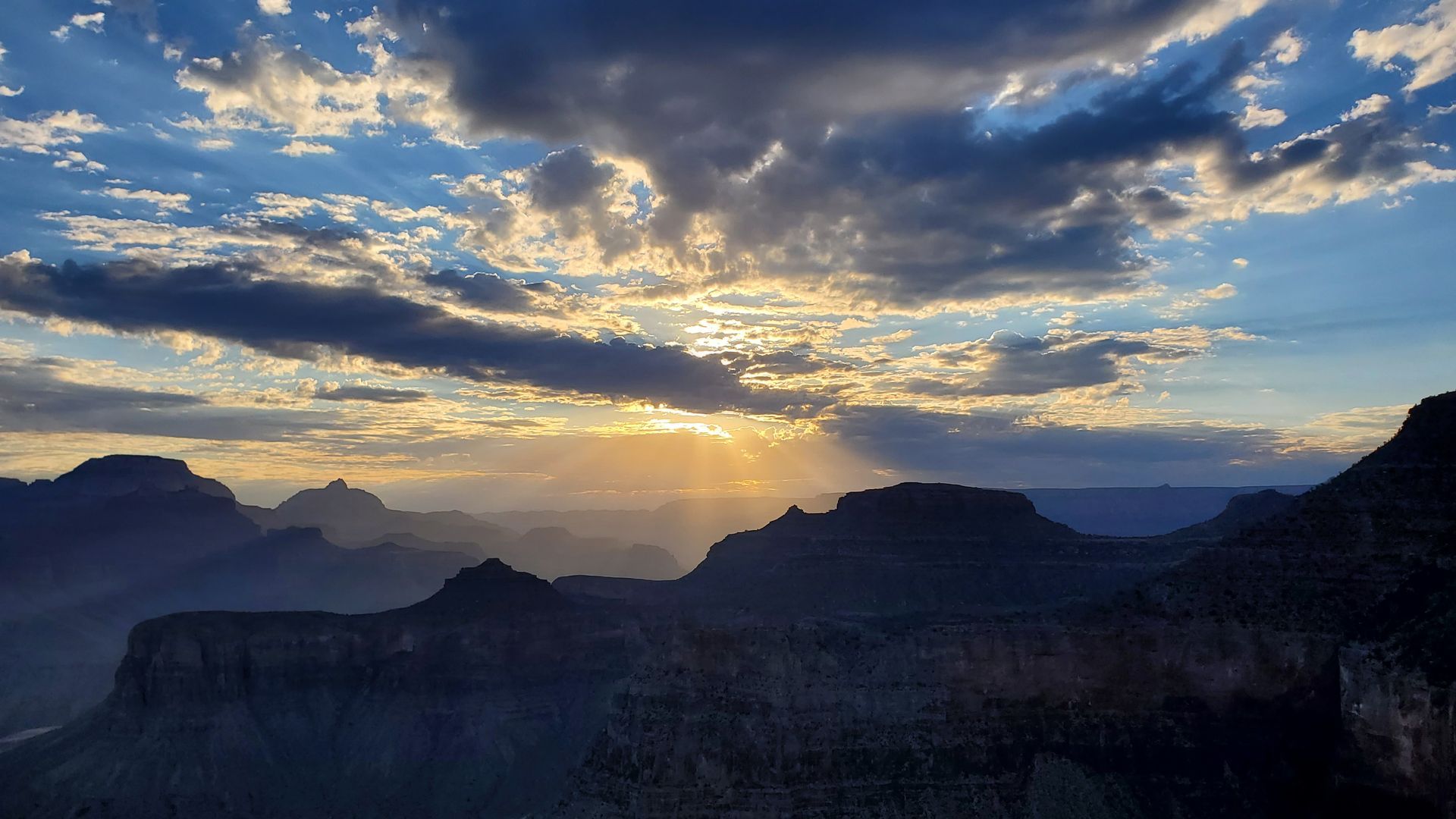The sun is shining through the clouds over the mountains