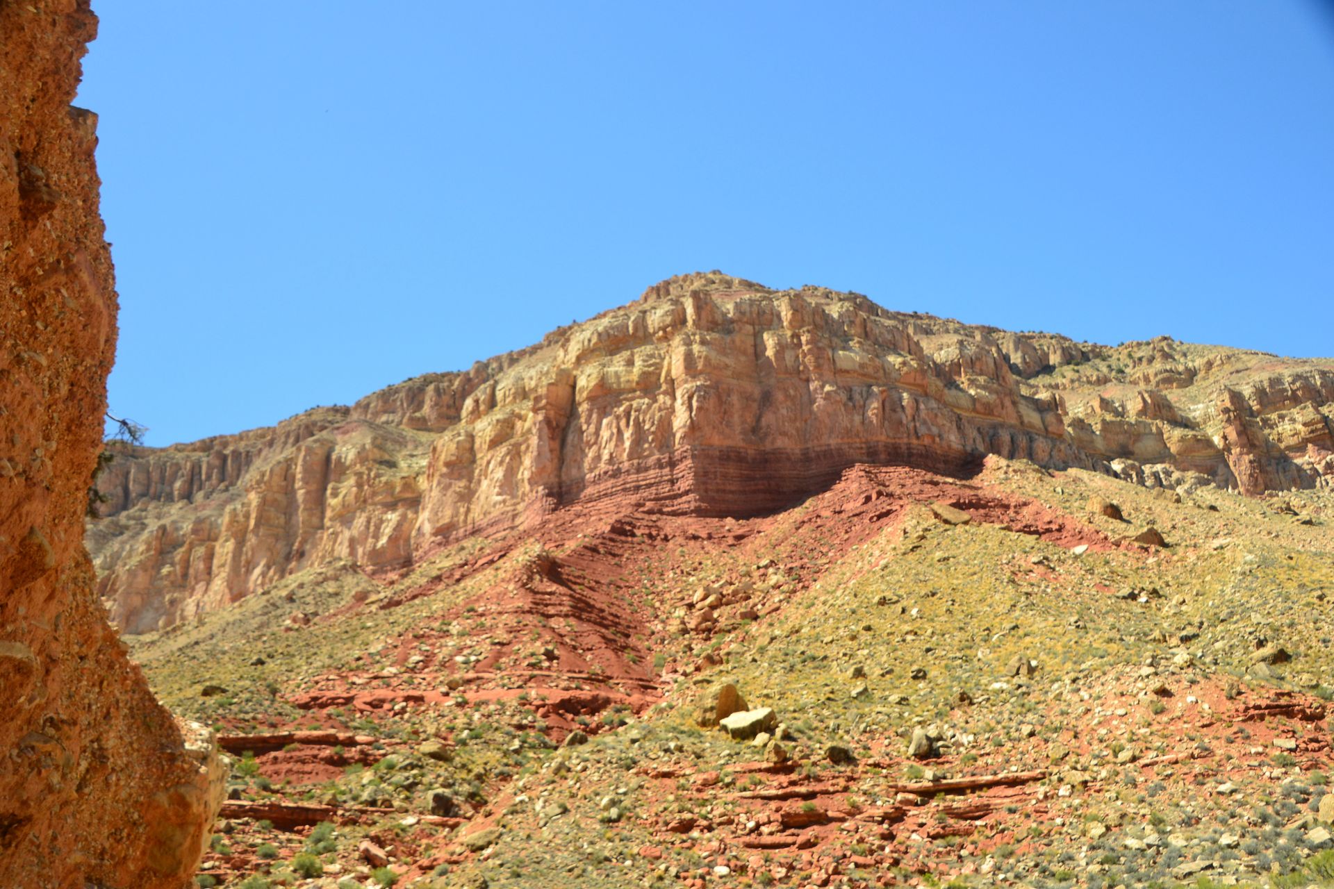 Colorful layered rock formations under a clear blue sky.
