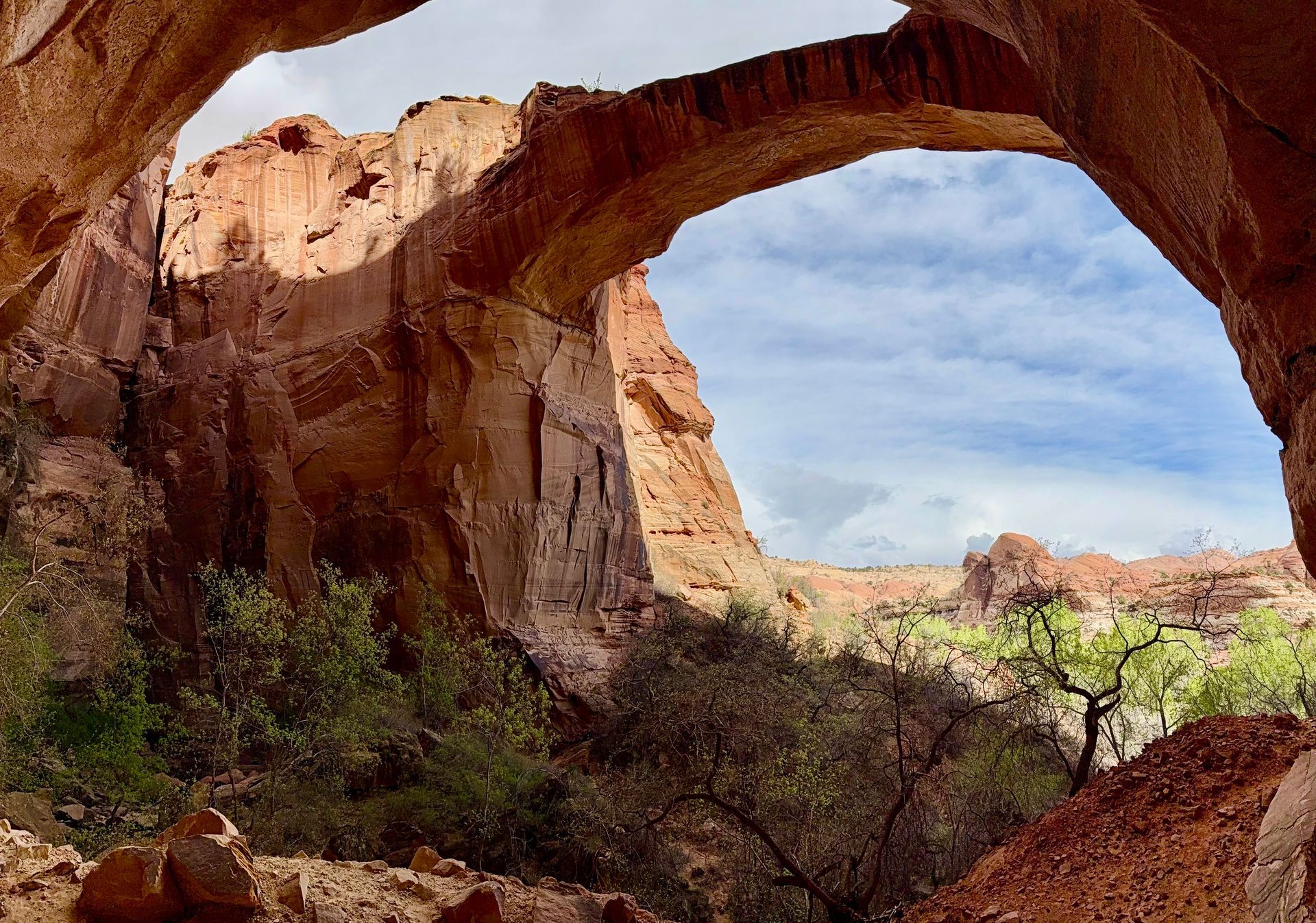 Natural sandstone arch frames a view of blue sky and canyon landscape.