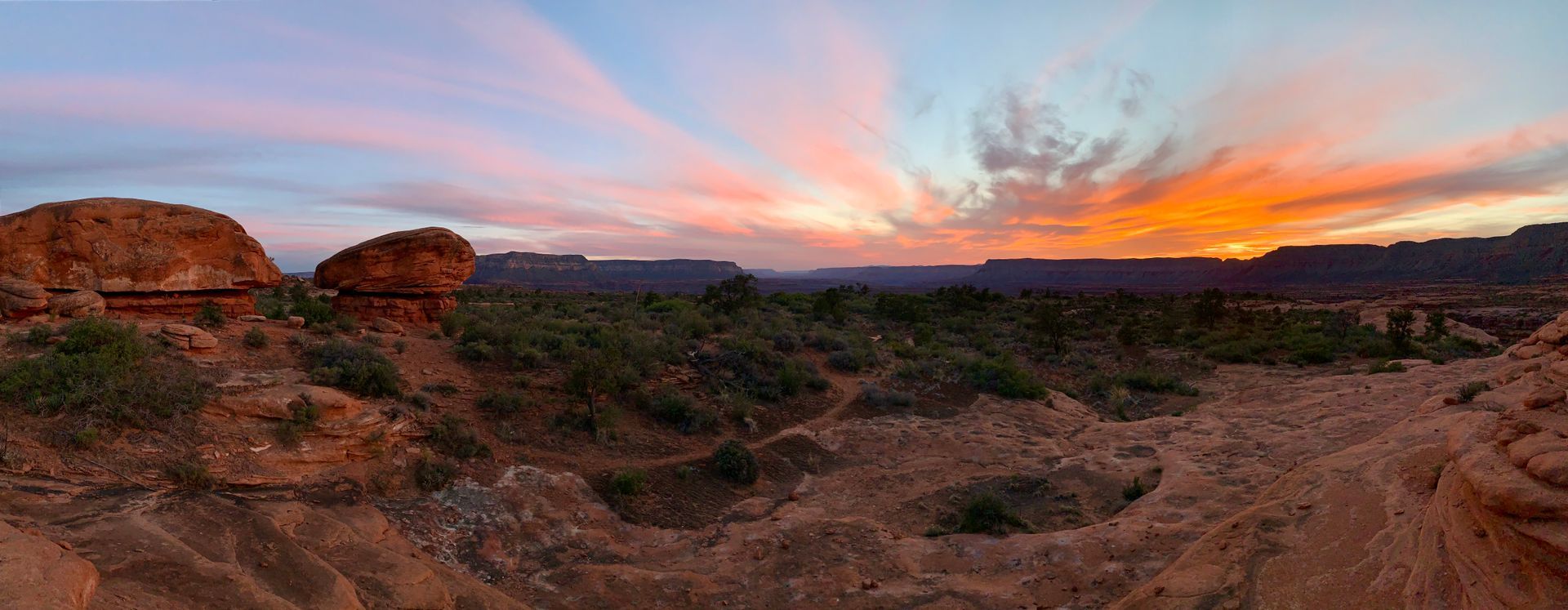 A sunset over a desert landscape with rocks and trees