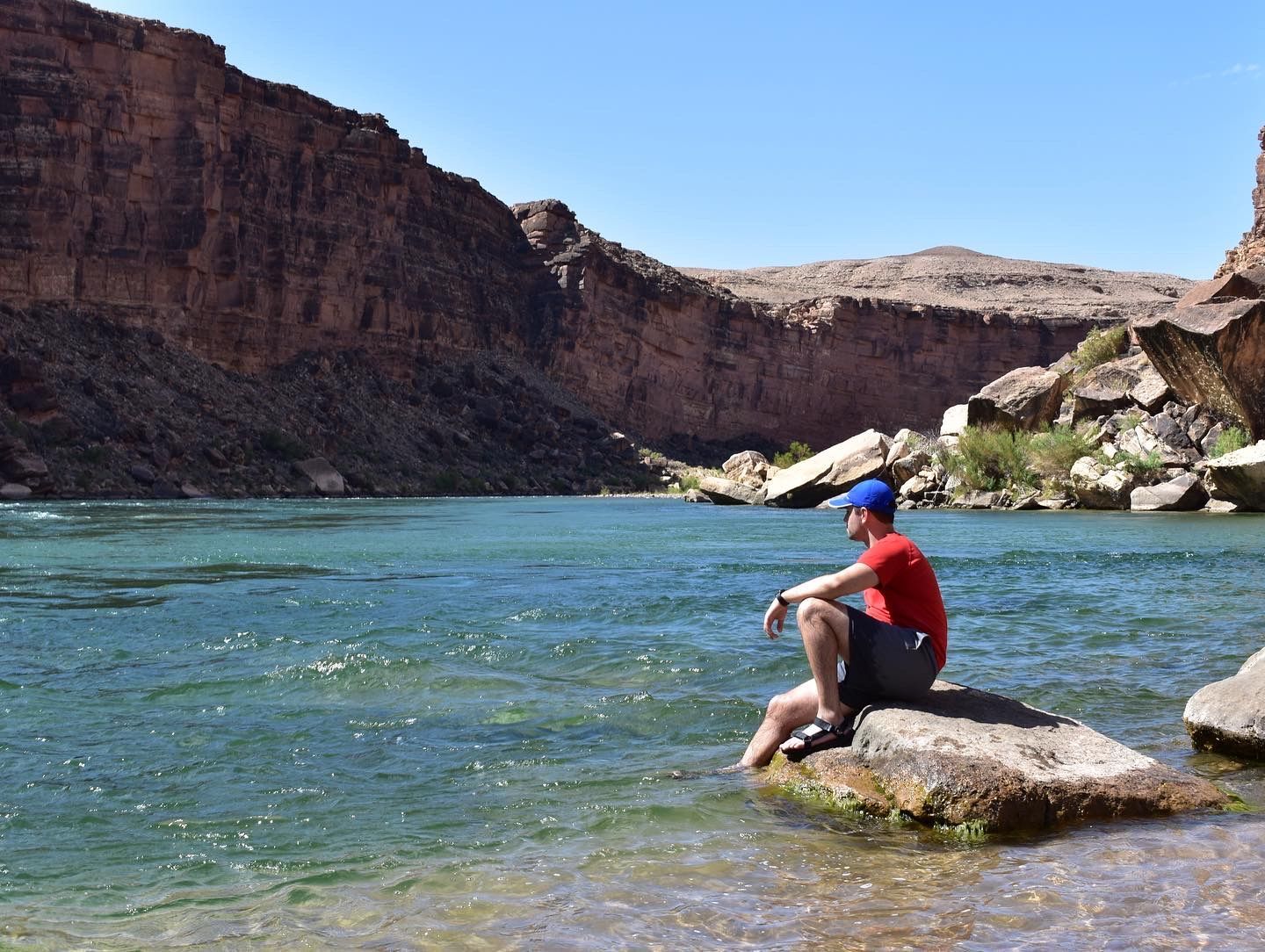 A man is sitting on a rock near a river