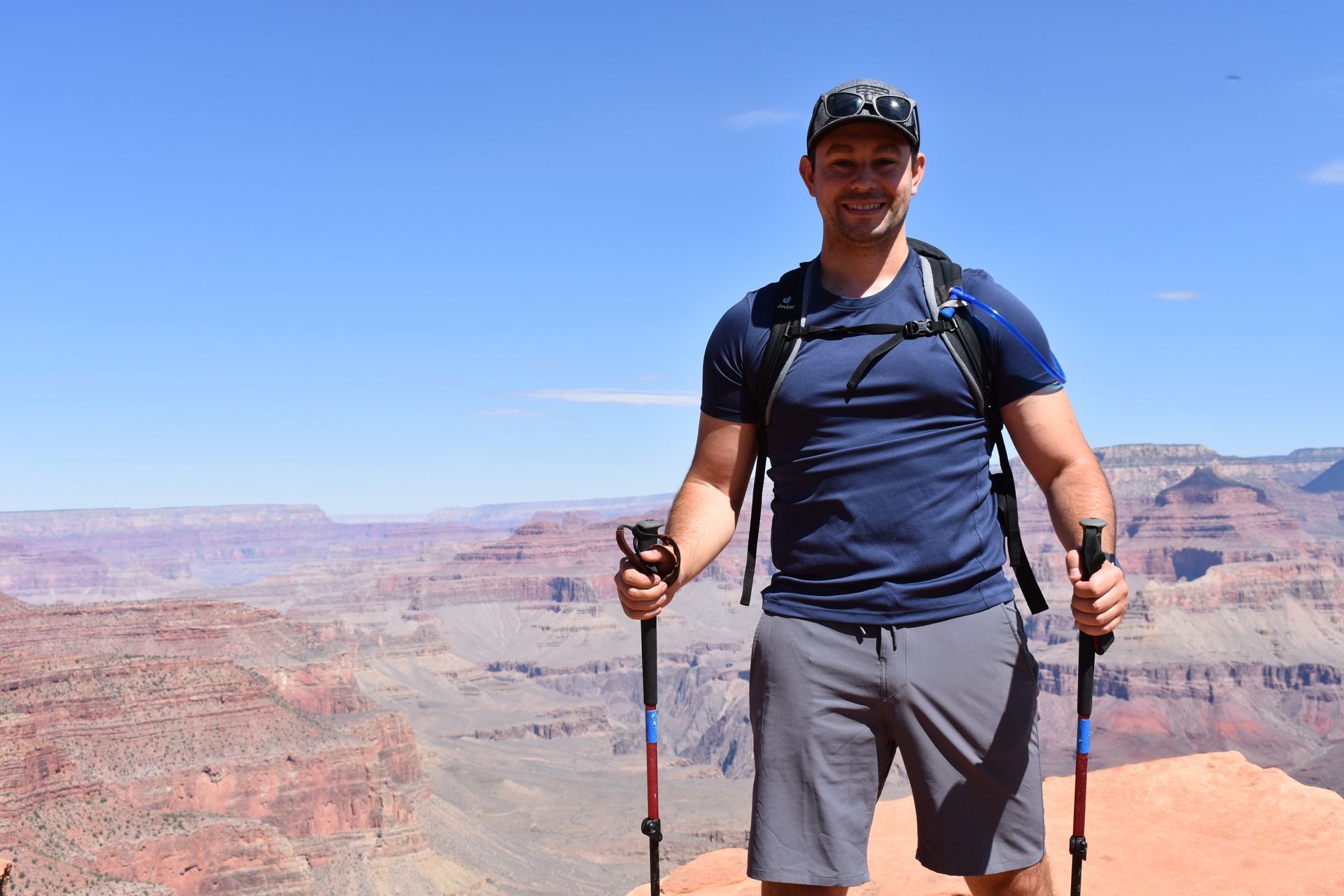 A man is standing on top of a mountain holding hiking poles.