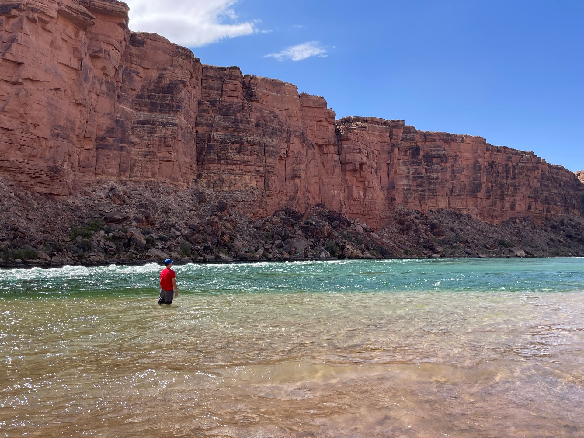 A man in a red shirt is standing in a body of water