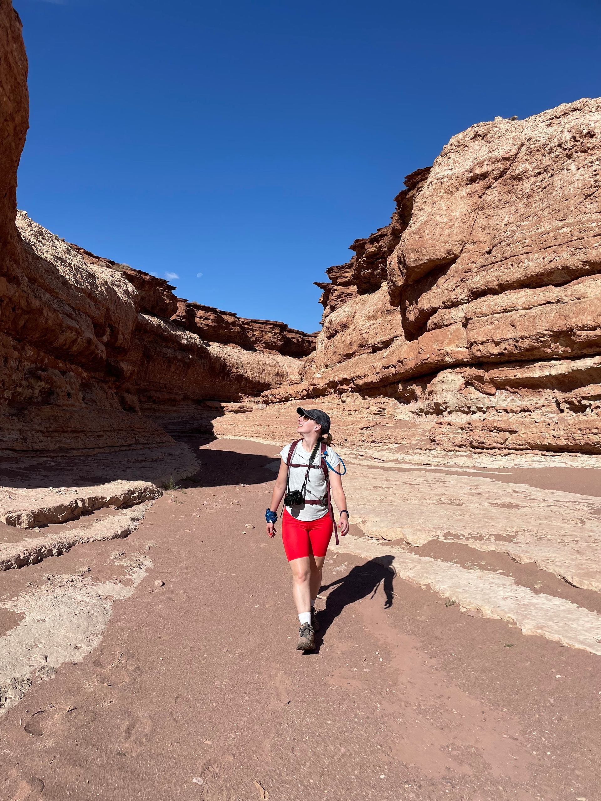 A woman is walking through a canyon in the desert.