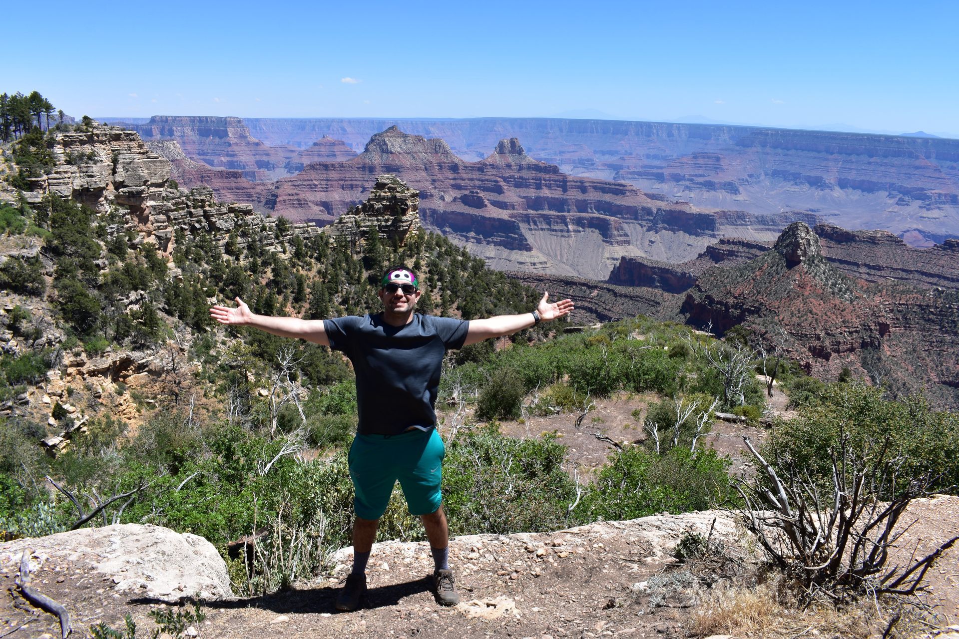 A man is standing on top of a mountain with his arms outstretched.