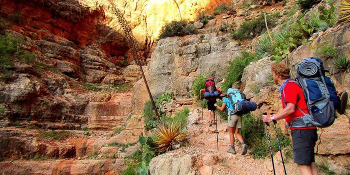 A group of people with backpacks are hiking up a mountain.