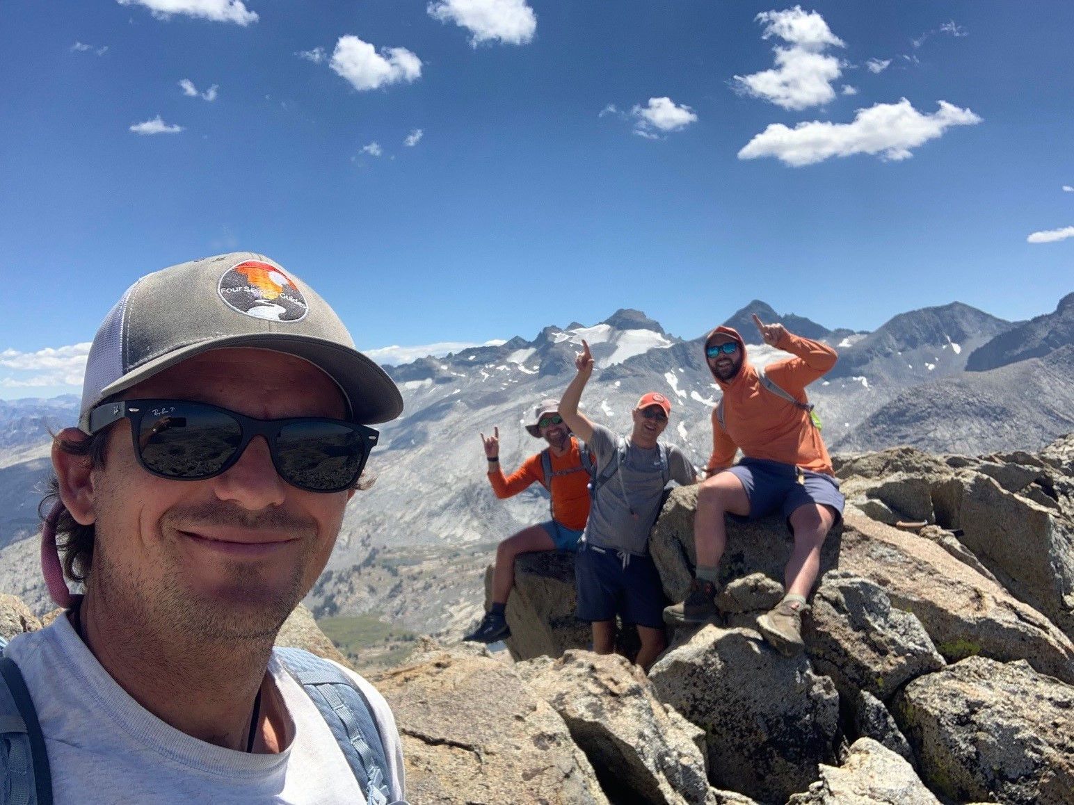 A group of people are posing for a picture on top of a mountain.