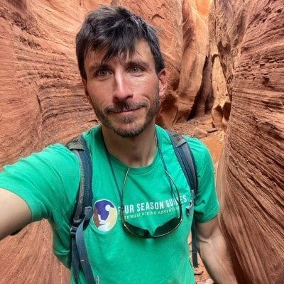 A man in a green shirt is taking a selfie in a canyon.