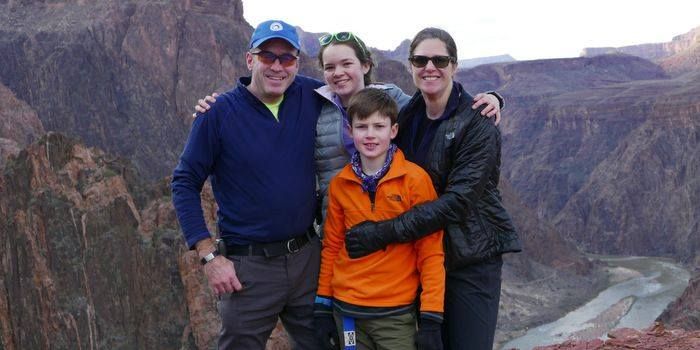 A family is posing for a picture on top of a canyon.