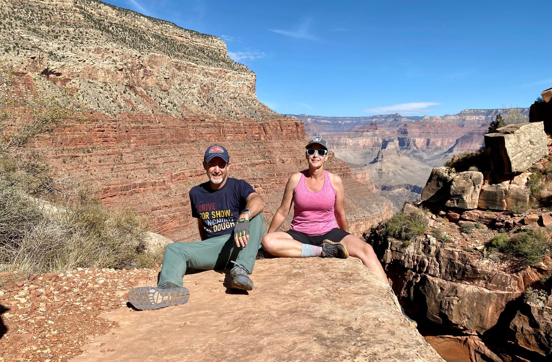 A man and a woman are sitting on top of a rock.
