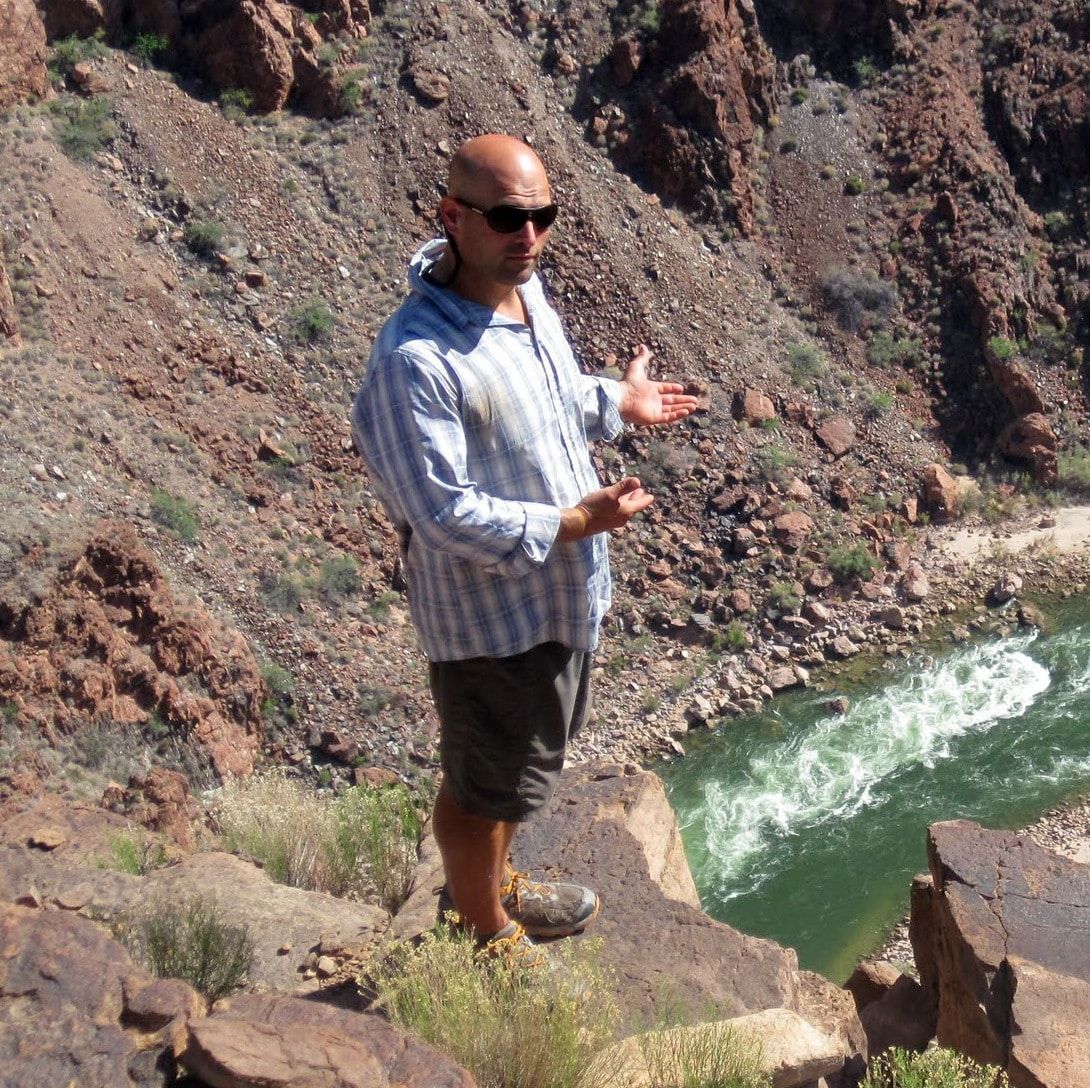 A man standing on a rocky cliff overlooking a river