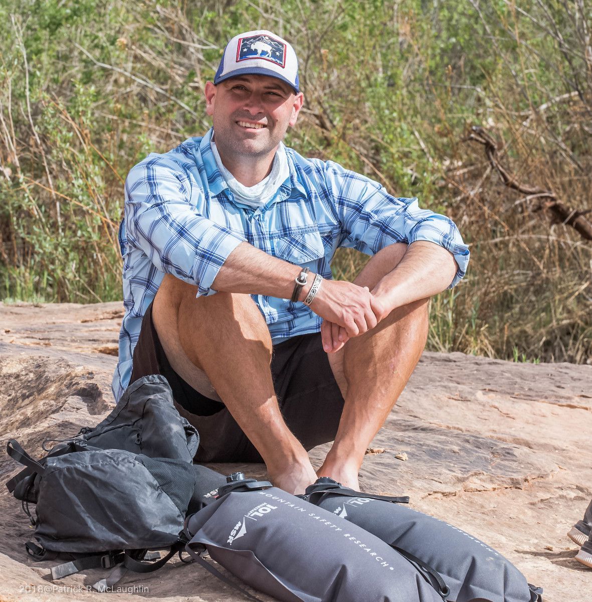 A man standing on a rocky cliff overlooking a river
