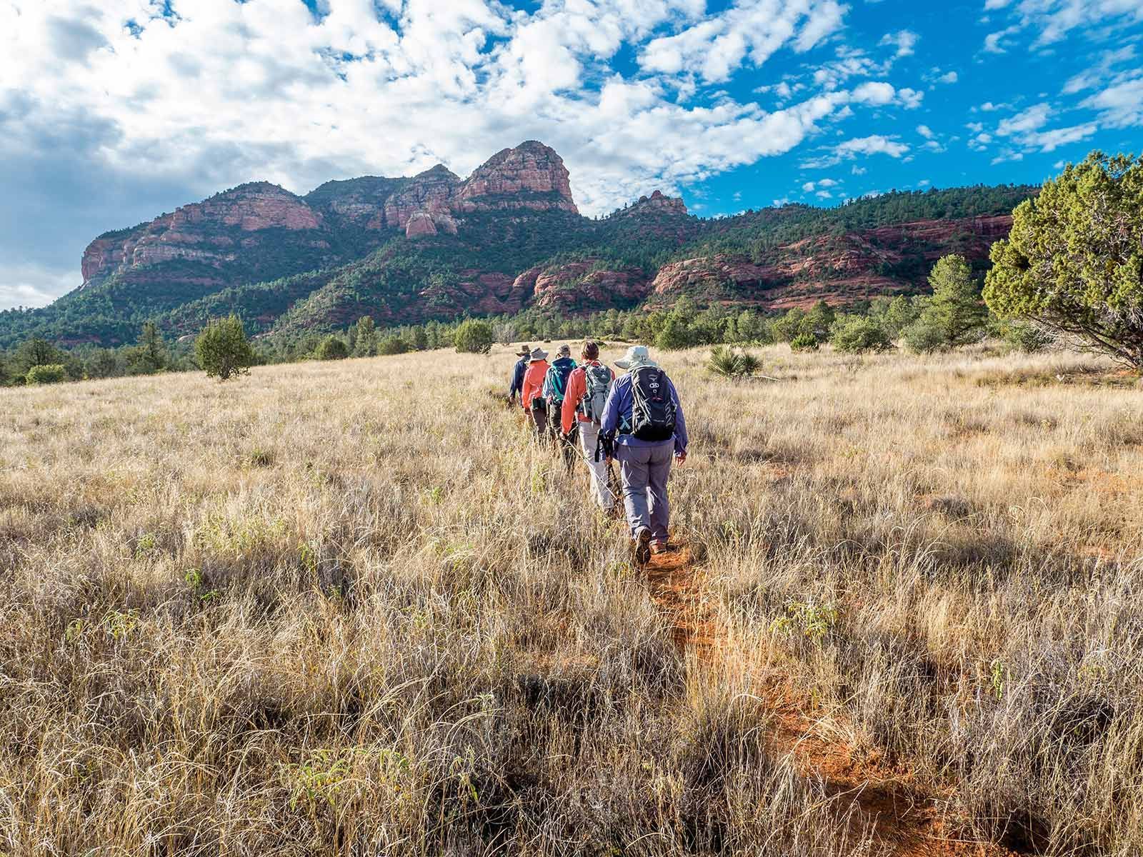 people walking through the fields to a mountain