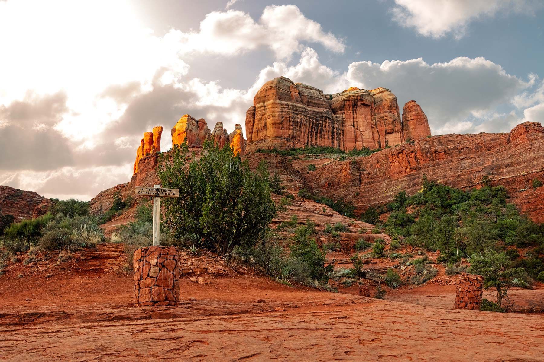 A desert landscape with a sign in the foreground and a mountain in the background.