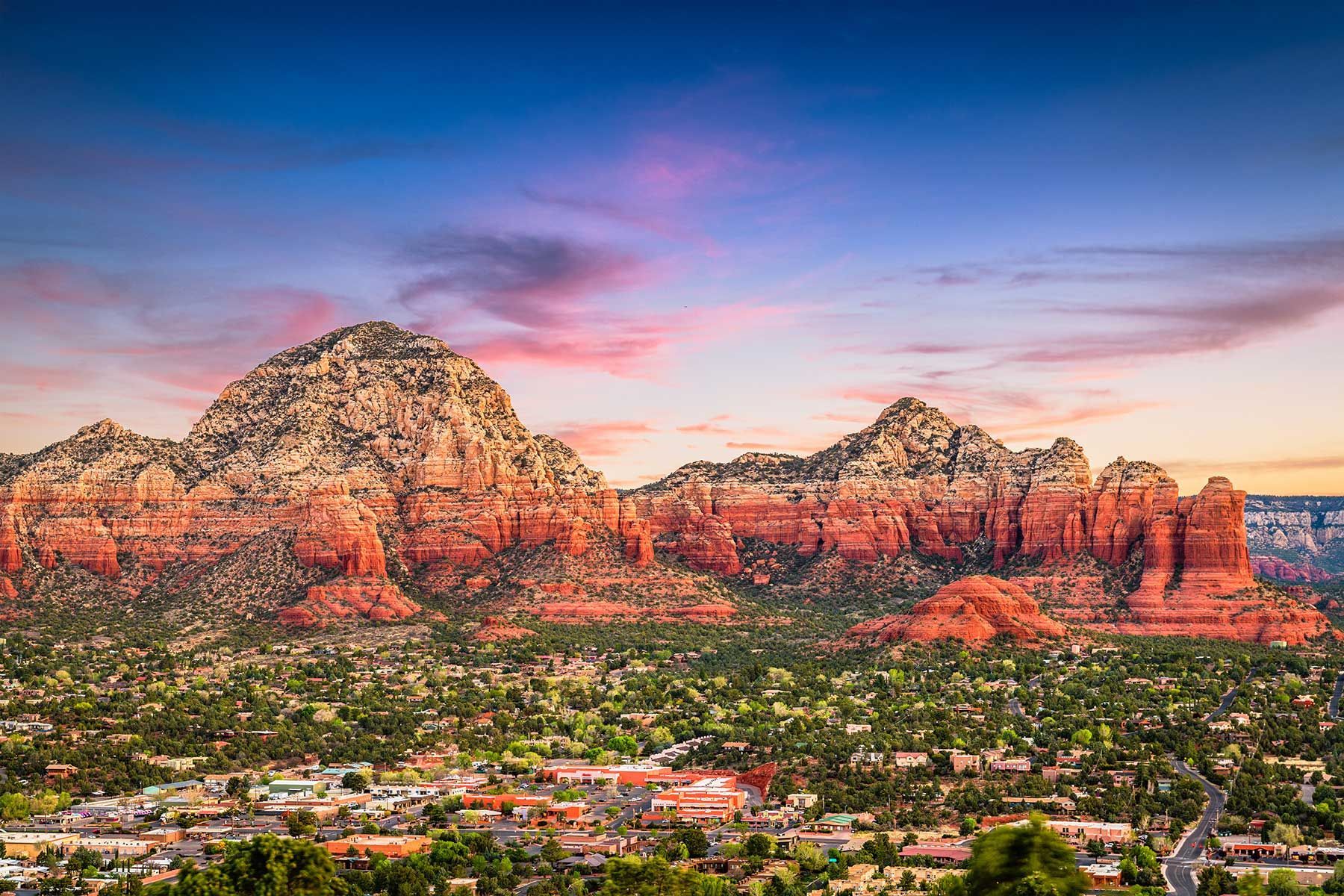 An aerial view of a city with mountains in the background at sunset.