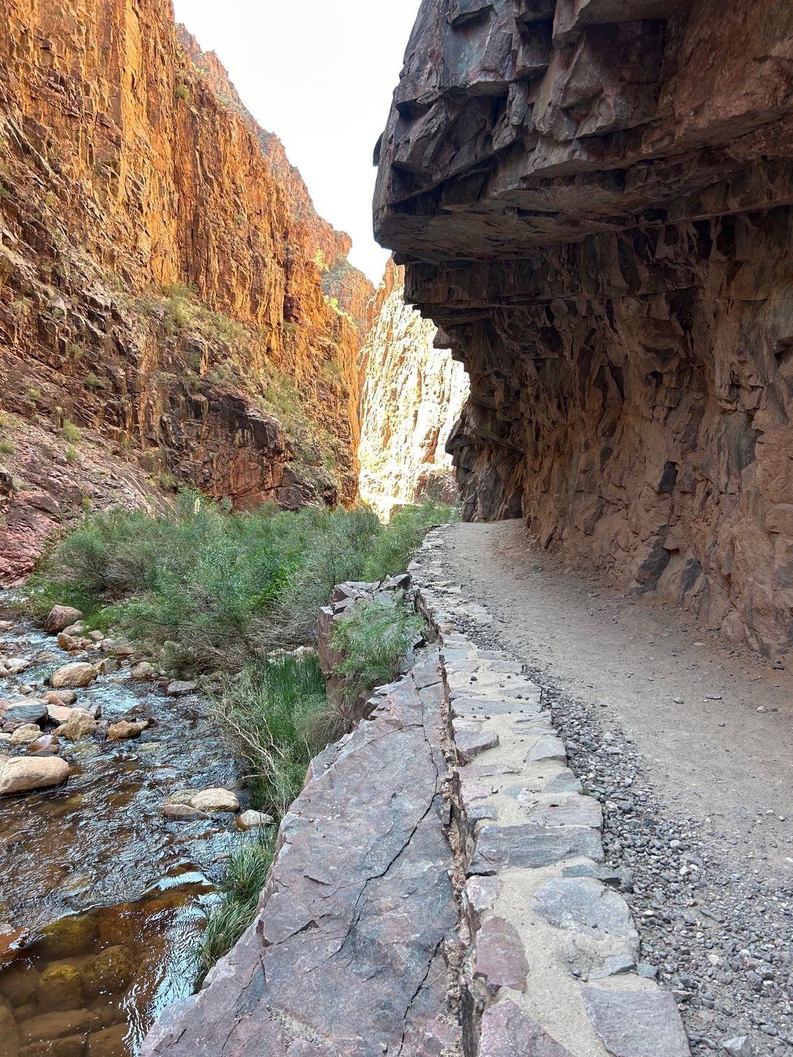 A stone path going through a canyon next to a river.