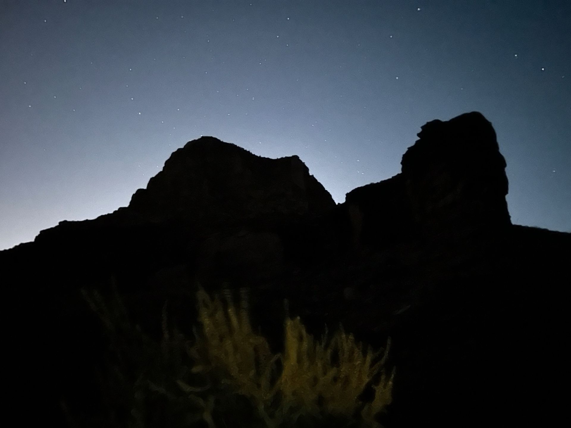 A mountain silhouetted against a starry night sky