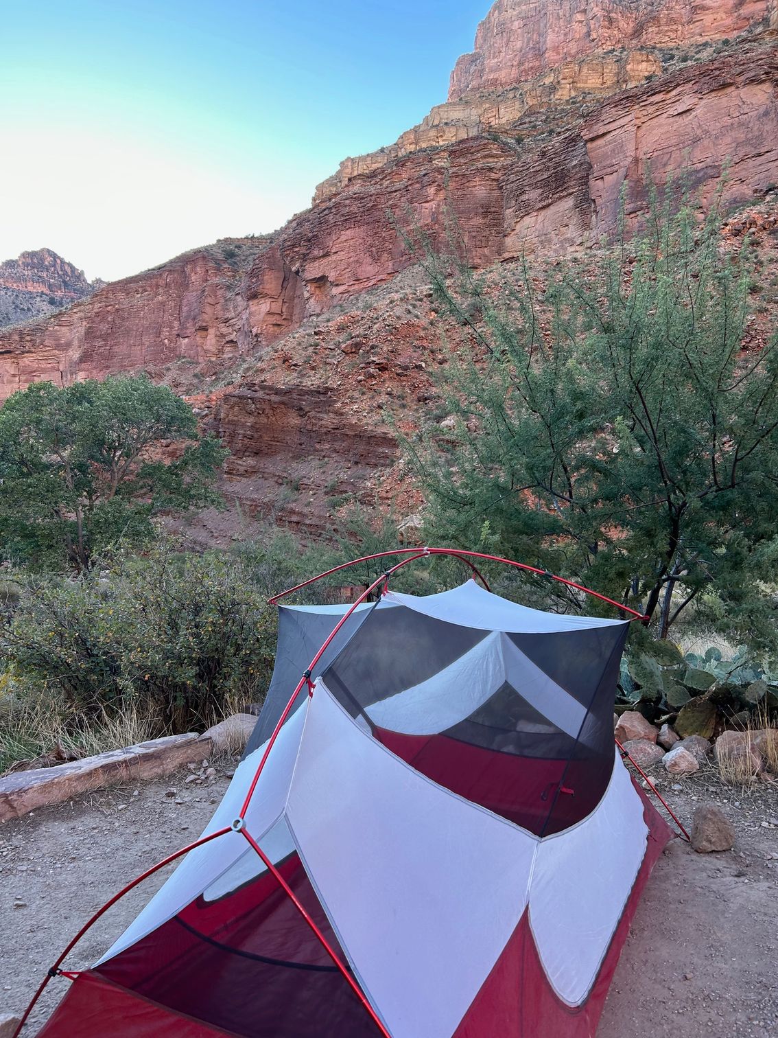 A red and white tent is sitting in front of a mountain.
