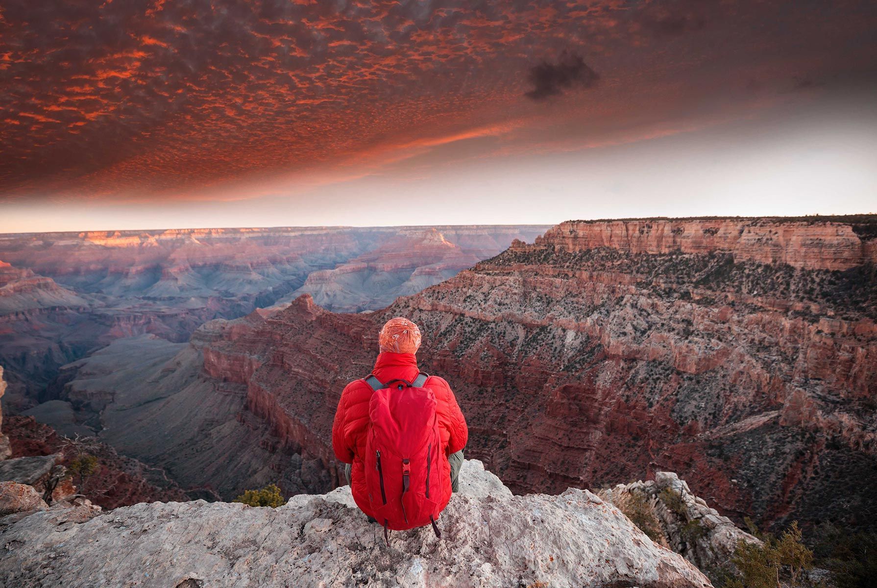 Sitting on top of a rocky cliff overlooking a canyon.