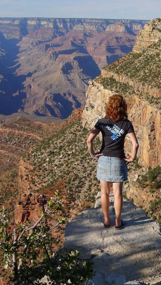 A woman is standing on a cliff overlooking a canyon.