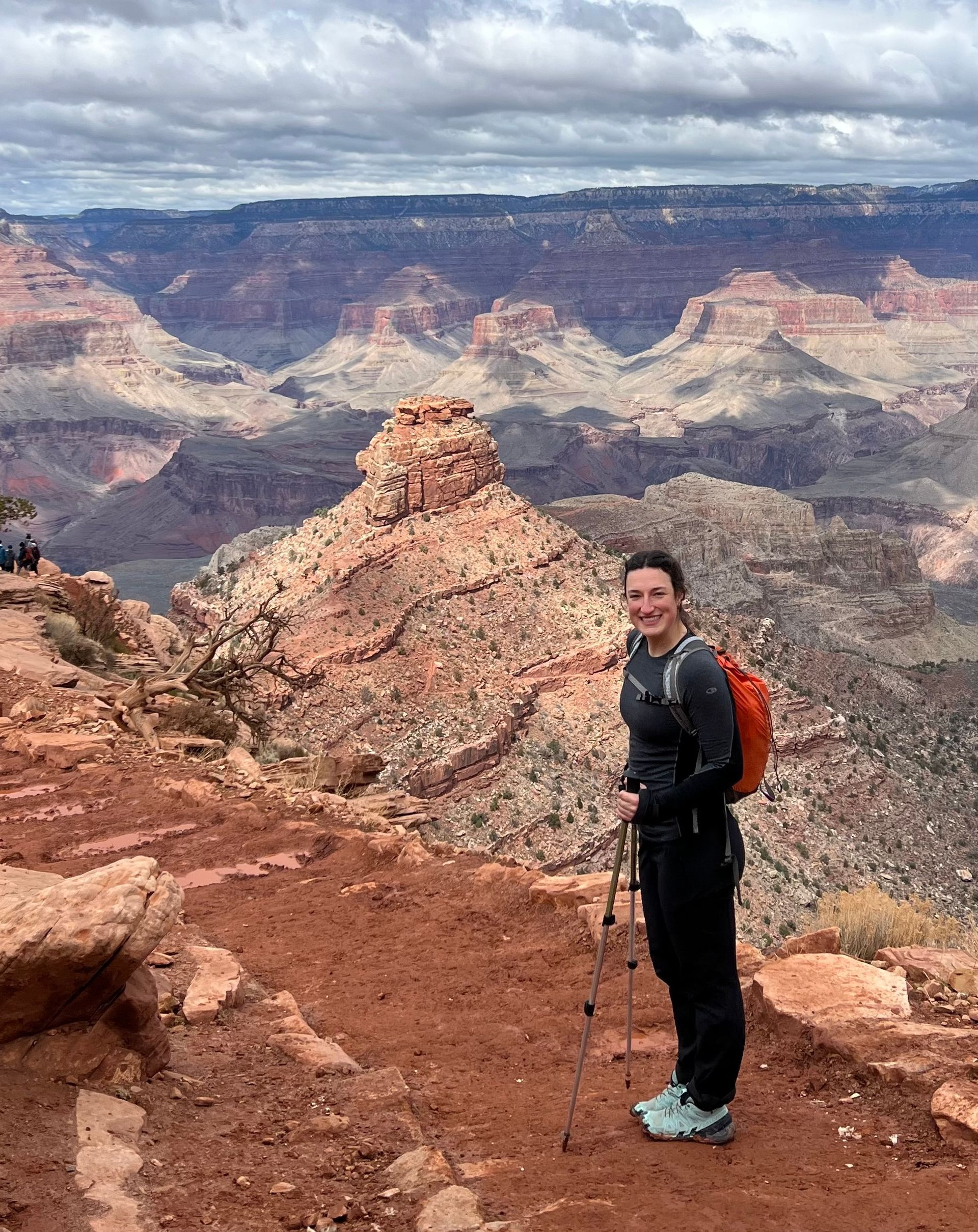 A man with a backpack is standing on top of a mountain.