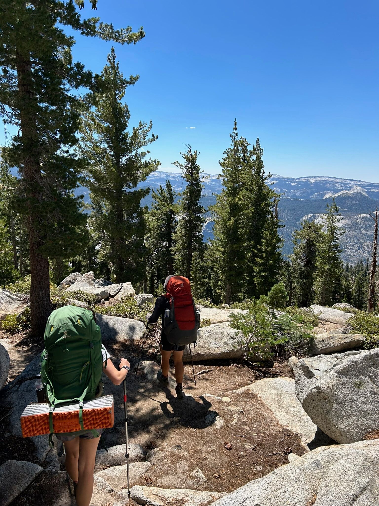 Two people with backpacks are hiking up a mountain.