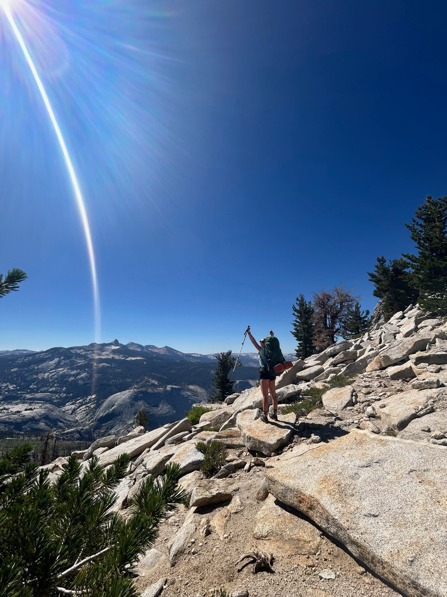 A person with a backpack is standing on top of a rocky mountain.