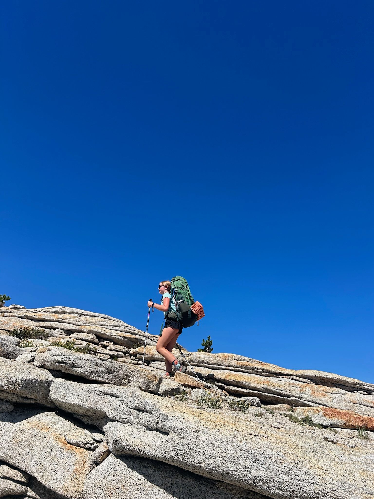 A person with a backpack is walking up a rocky hill.