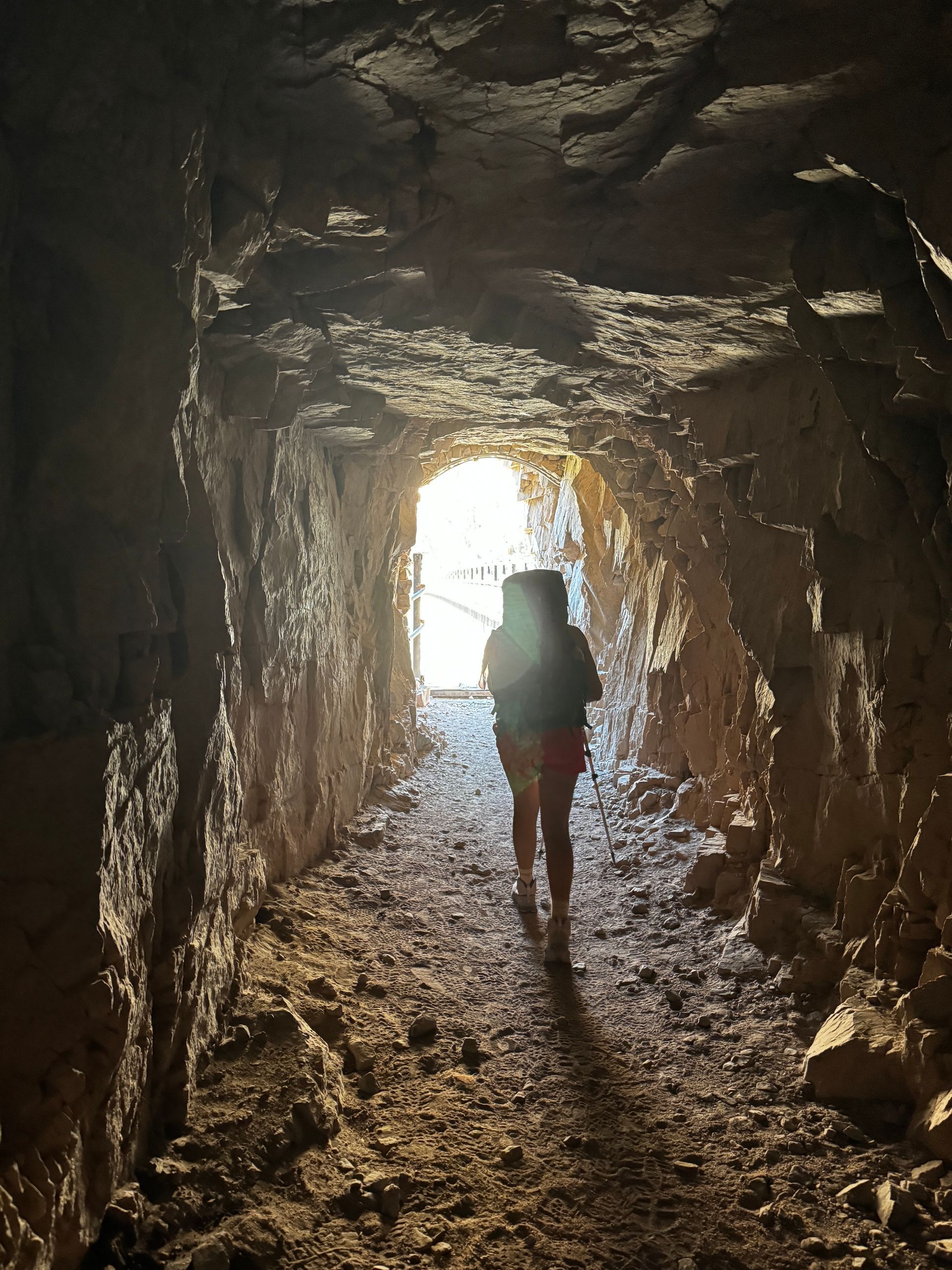 A person is walking through a tunnel with a light at the end