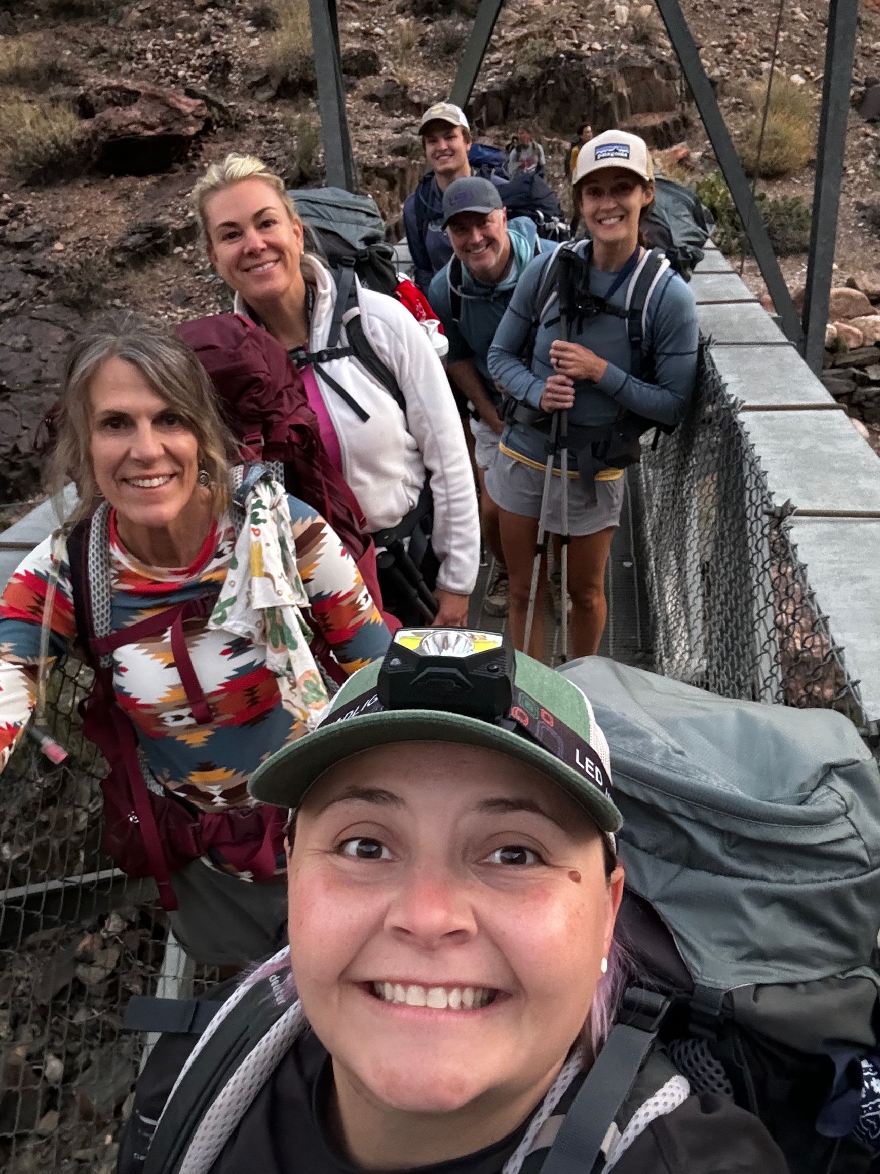 A group of people are standing on a bridge and smiling.