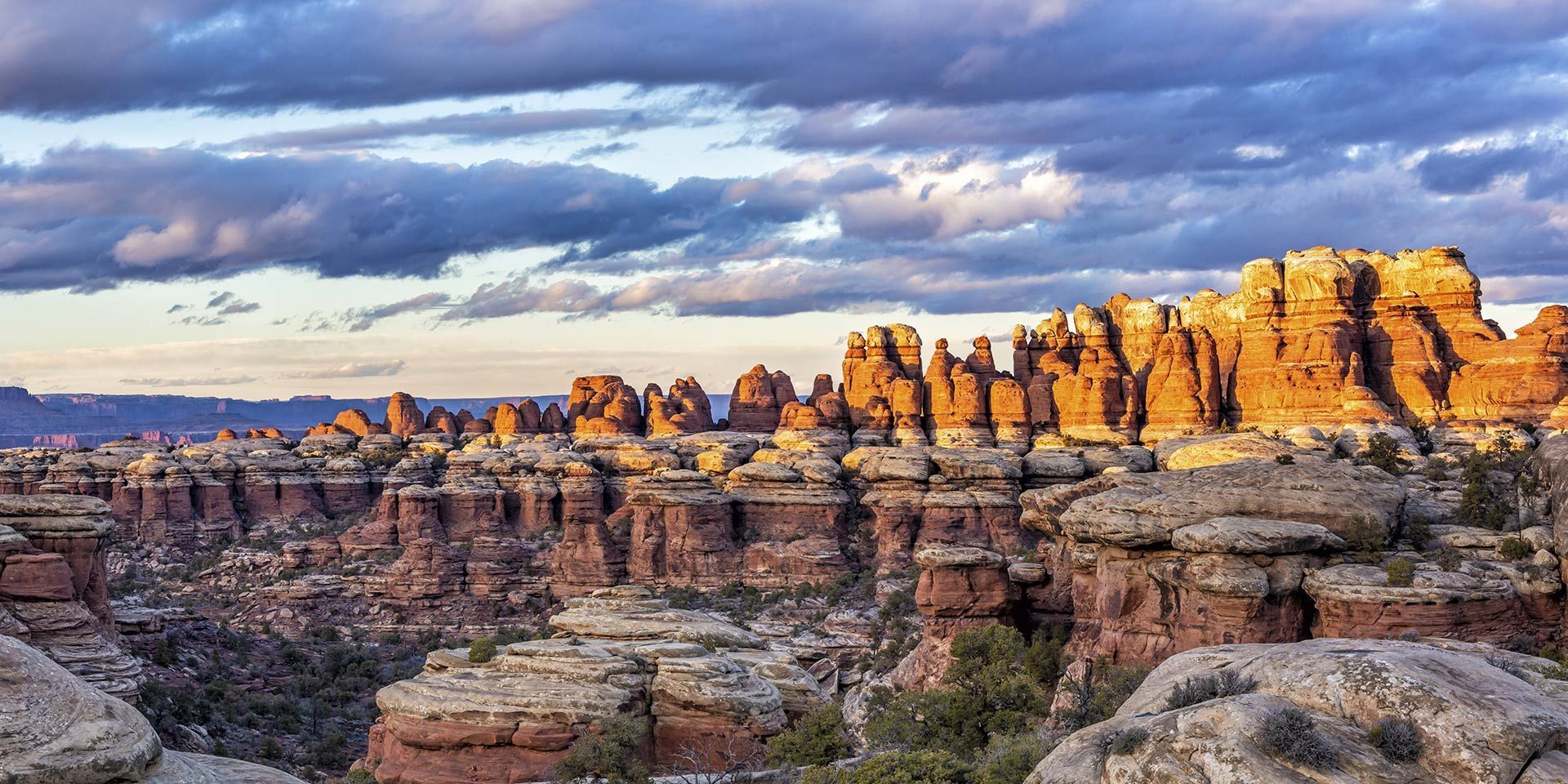 A large rock formation in the middle of a canyon with a cloudy sky in the background.