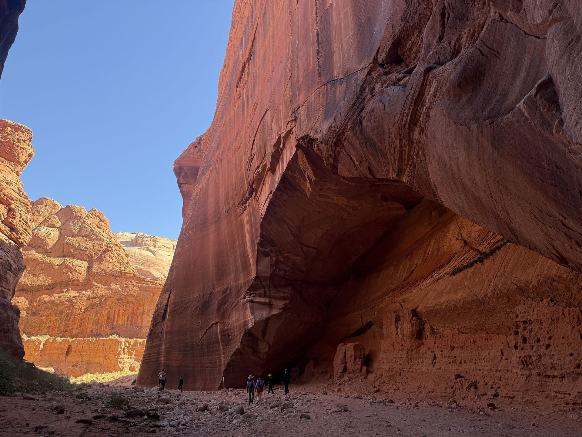 Red rock canyon with people walking, blue sky visible.
